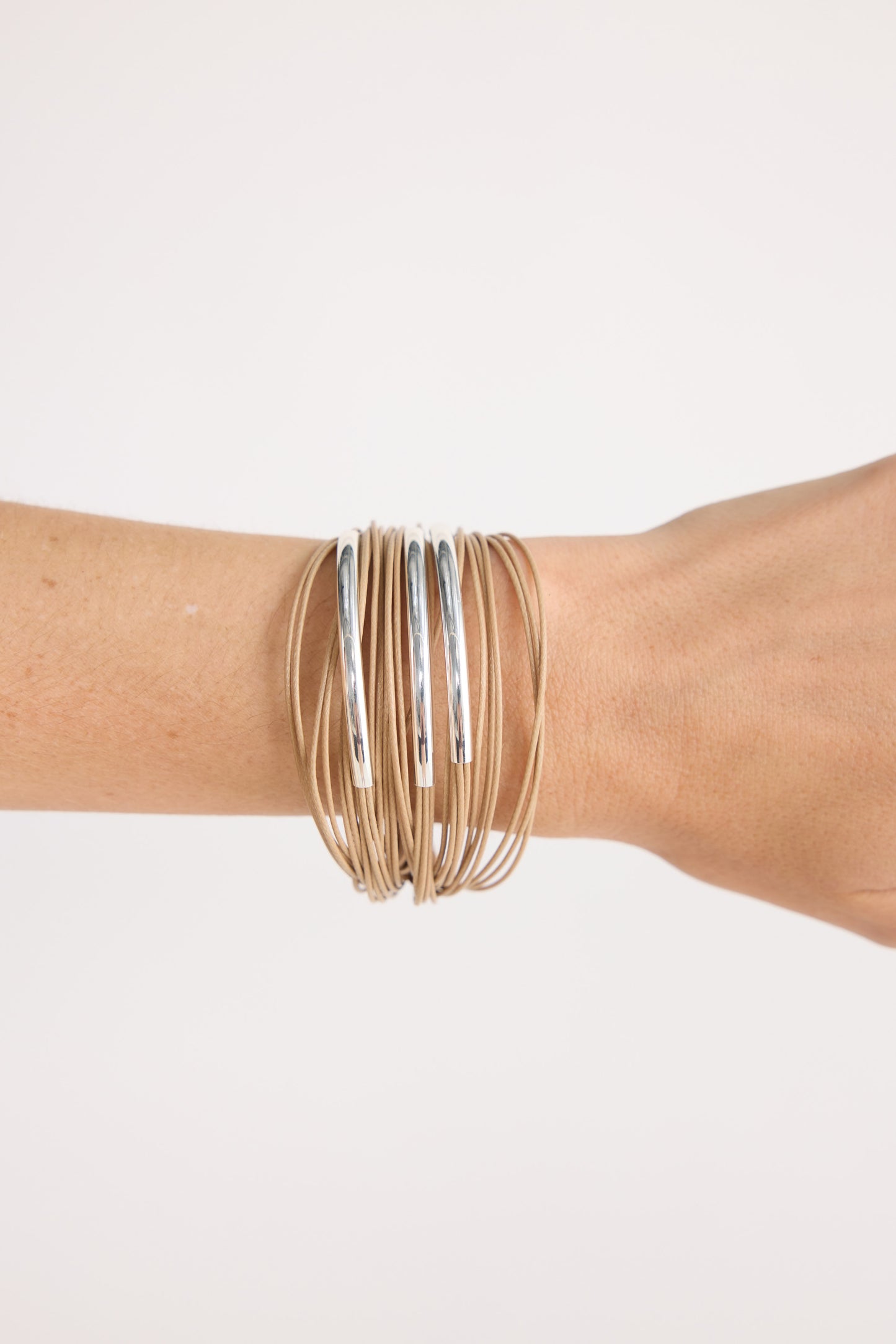 Model wearing Shakira Bracelet in camel with metal accent bars, close-up on-wrist view on neutral background
