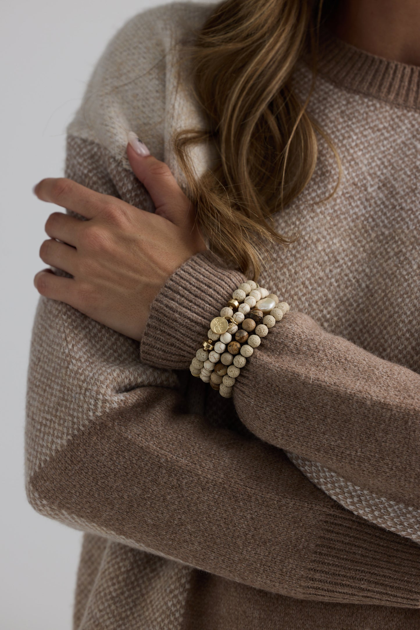 Model wearing Solaro Stack Bracelet in natural with natural stones and mother of pearl feature bead, side on-wrist view on neutral background