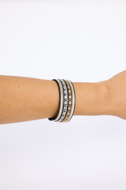 Model wearing Ballina Bracelet in black with layered textures and embellished detailing, on-wrist view on neutral background