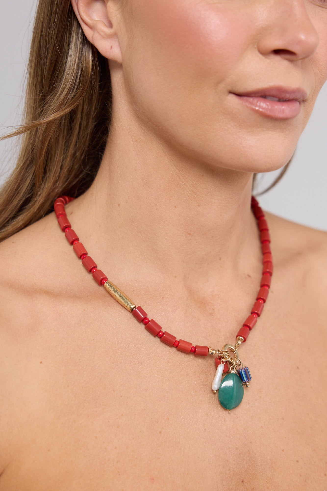 Close-up of the Elias Necklace in Aqua W Red worn at the neckline, showing the dangling charm cluster detail