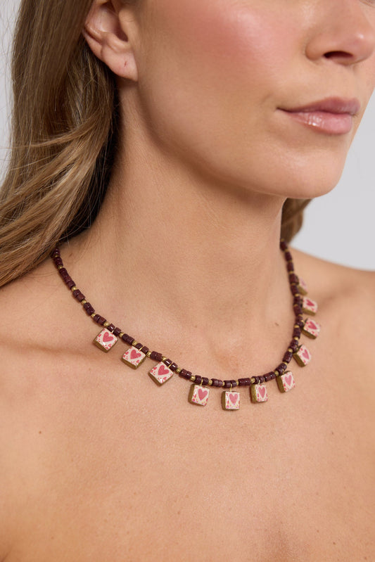 Close-up of the Love Sick Necklace in Red worn at the neckline, showing the heart charms in detail