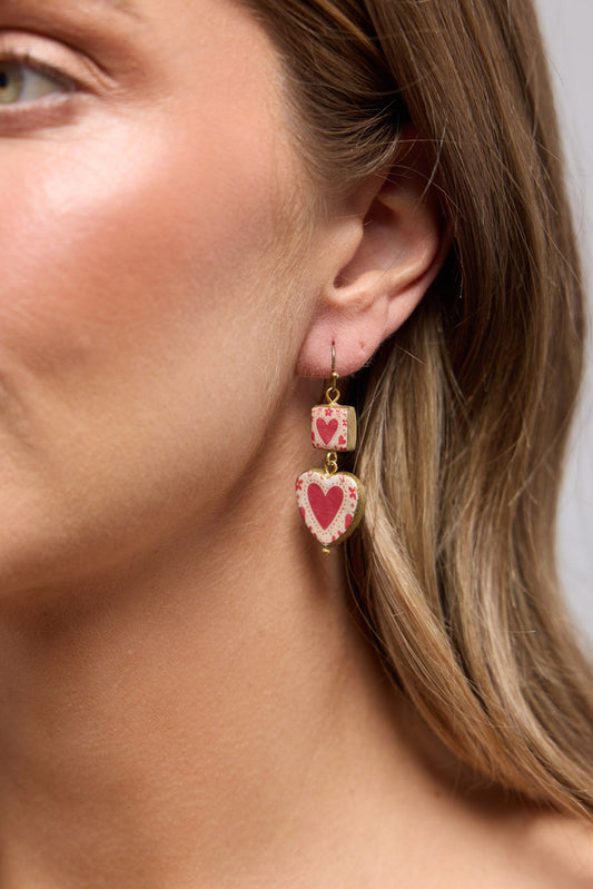 Close-up of the Love Sick Earrings in Red worn on the ear, showing the heart motif detail