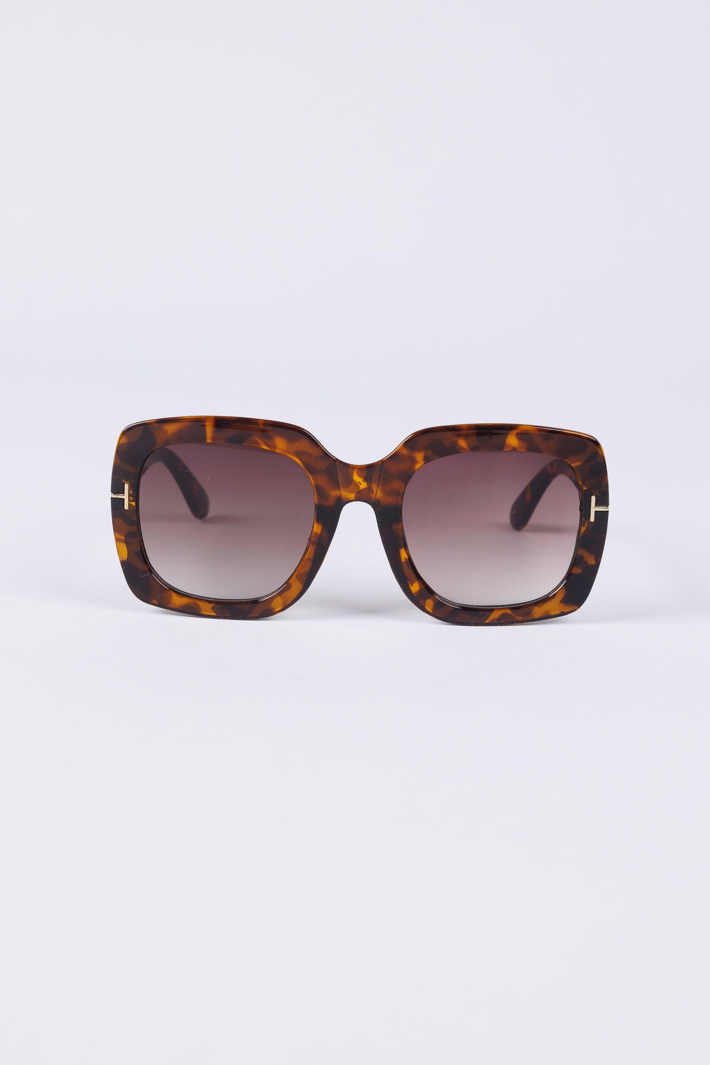 Sunglasses with tortoiseshell frame and gradient lenses on a white background