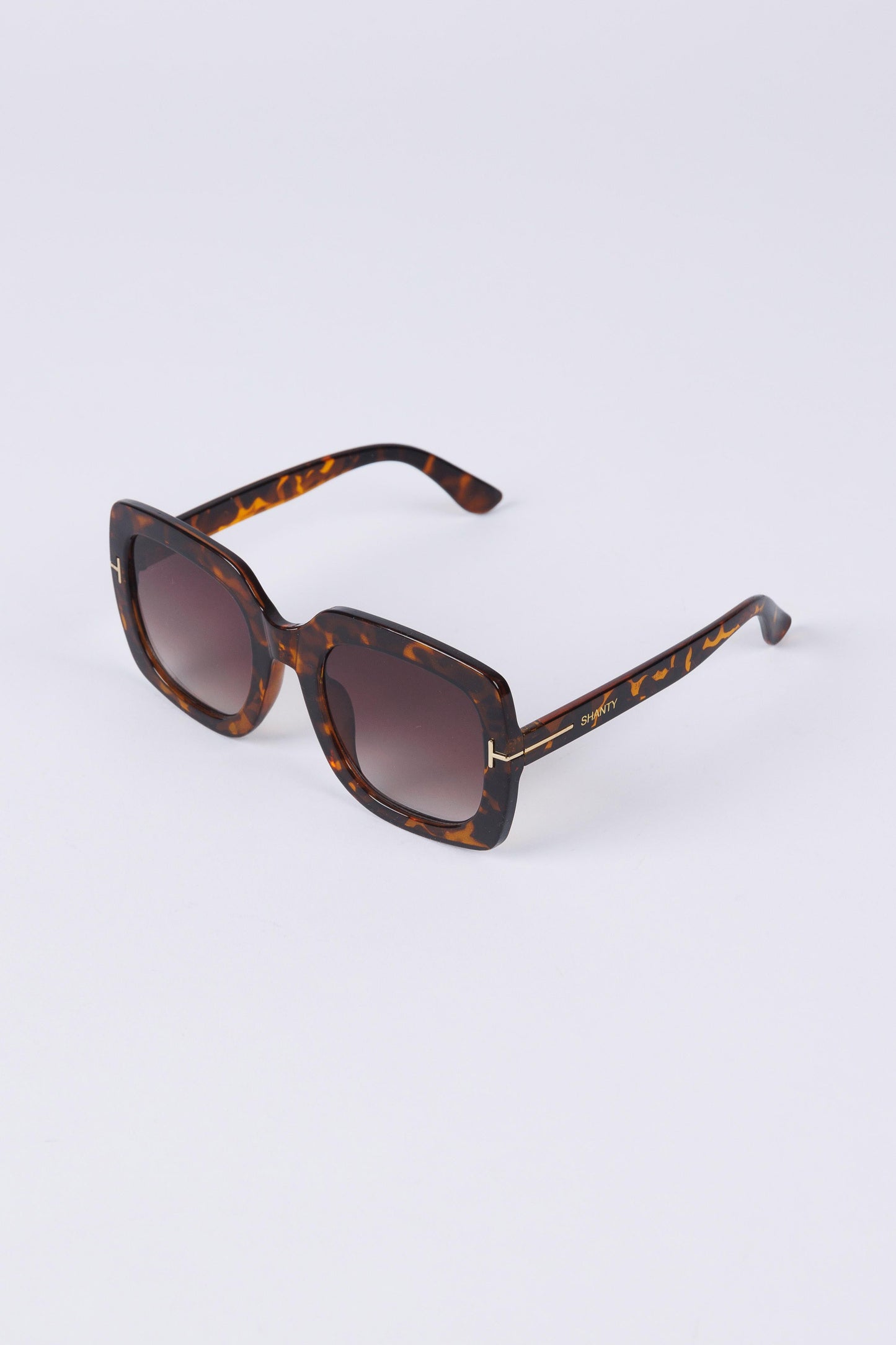 Sunglasses with tortoiseshell frame and brown gradient lenses on a white background