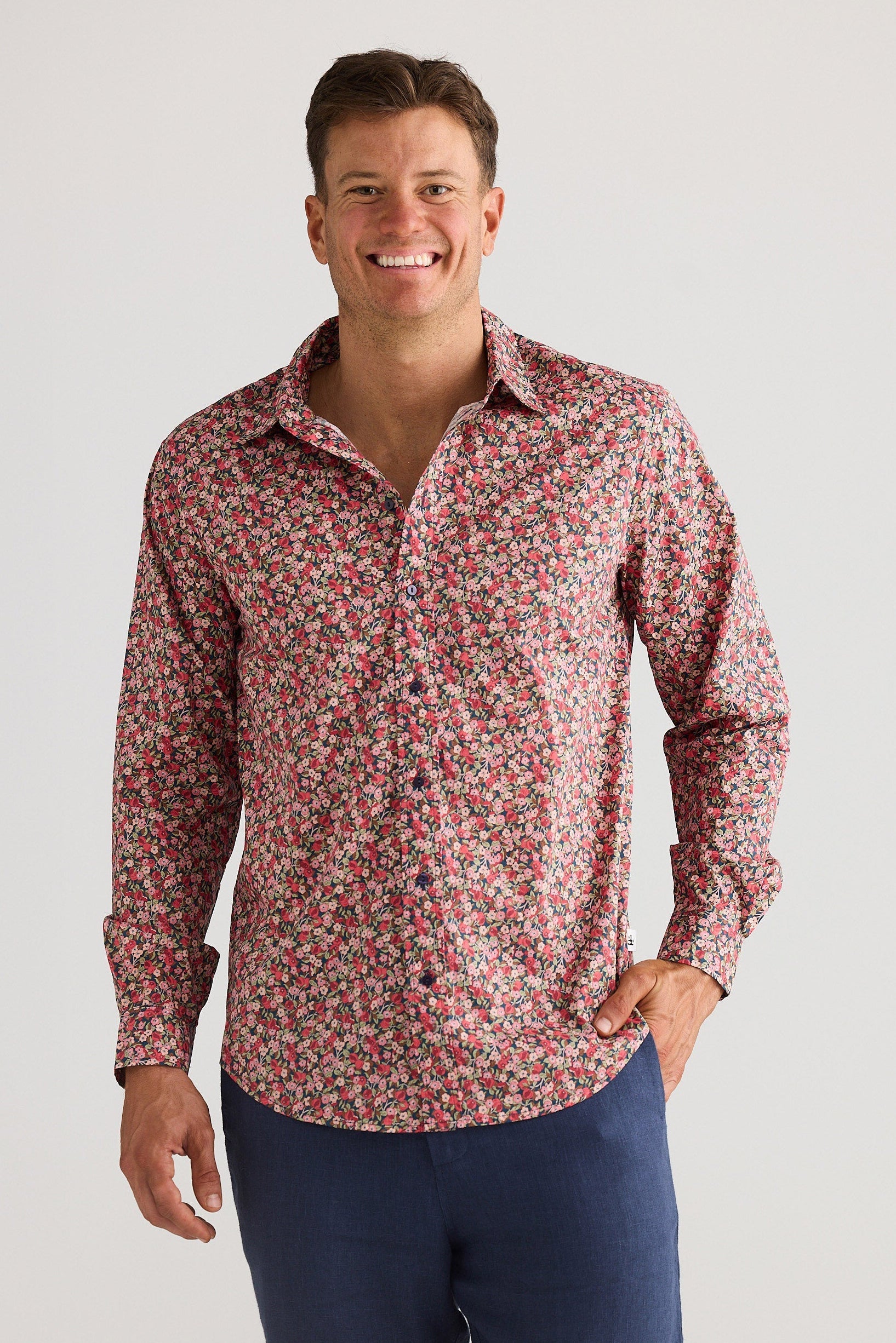 Man wearing a red floral shirt and navy shorts on a white background
