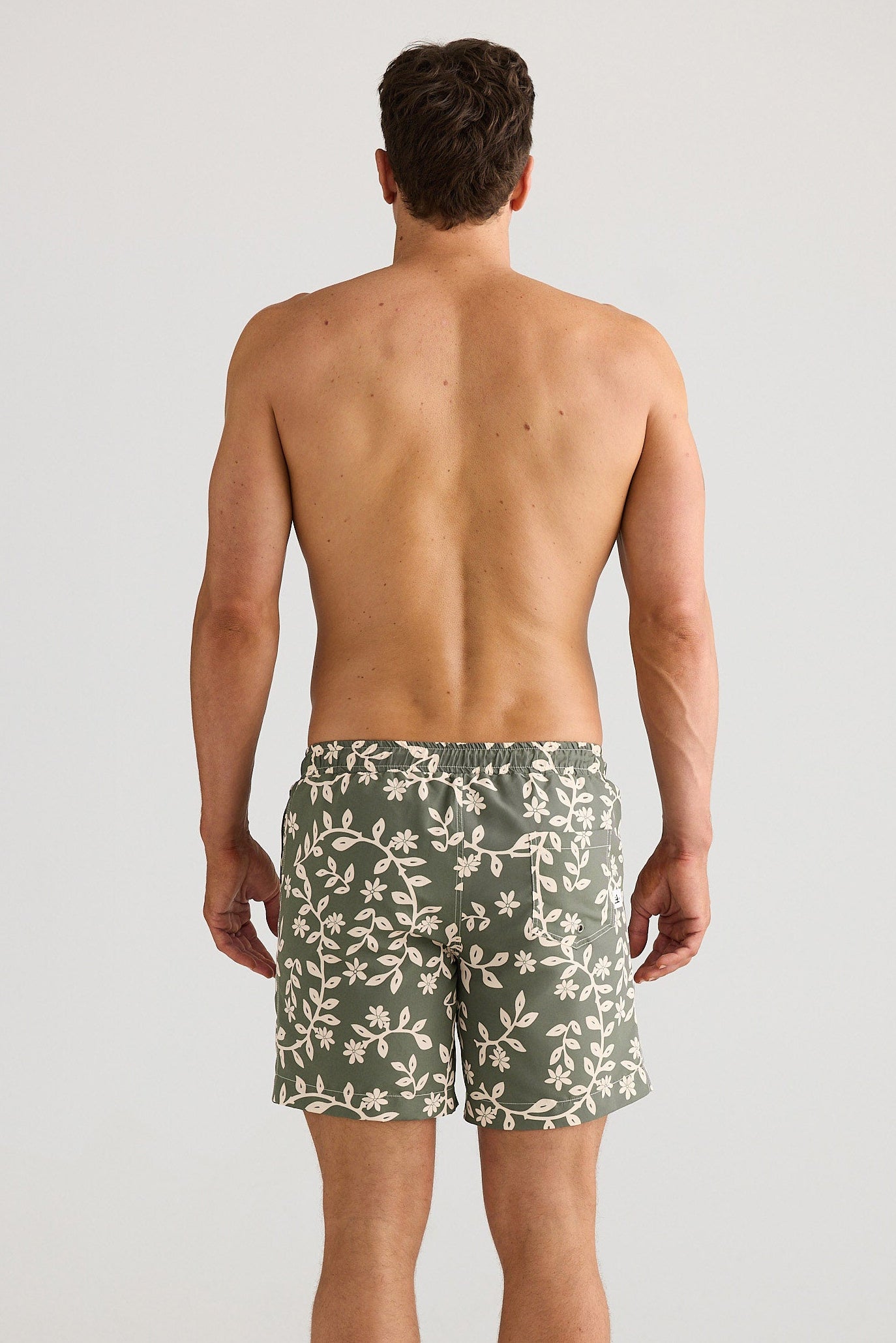 Man wearing green camouflage swim shorts on a white background