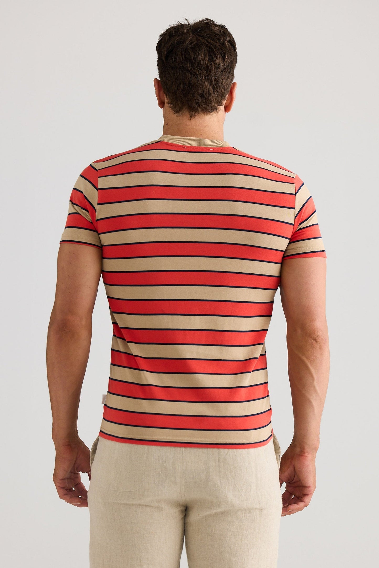 Man wearing a red and beige striped shirt against a white background