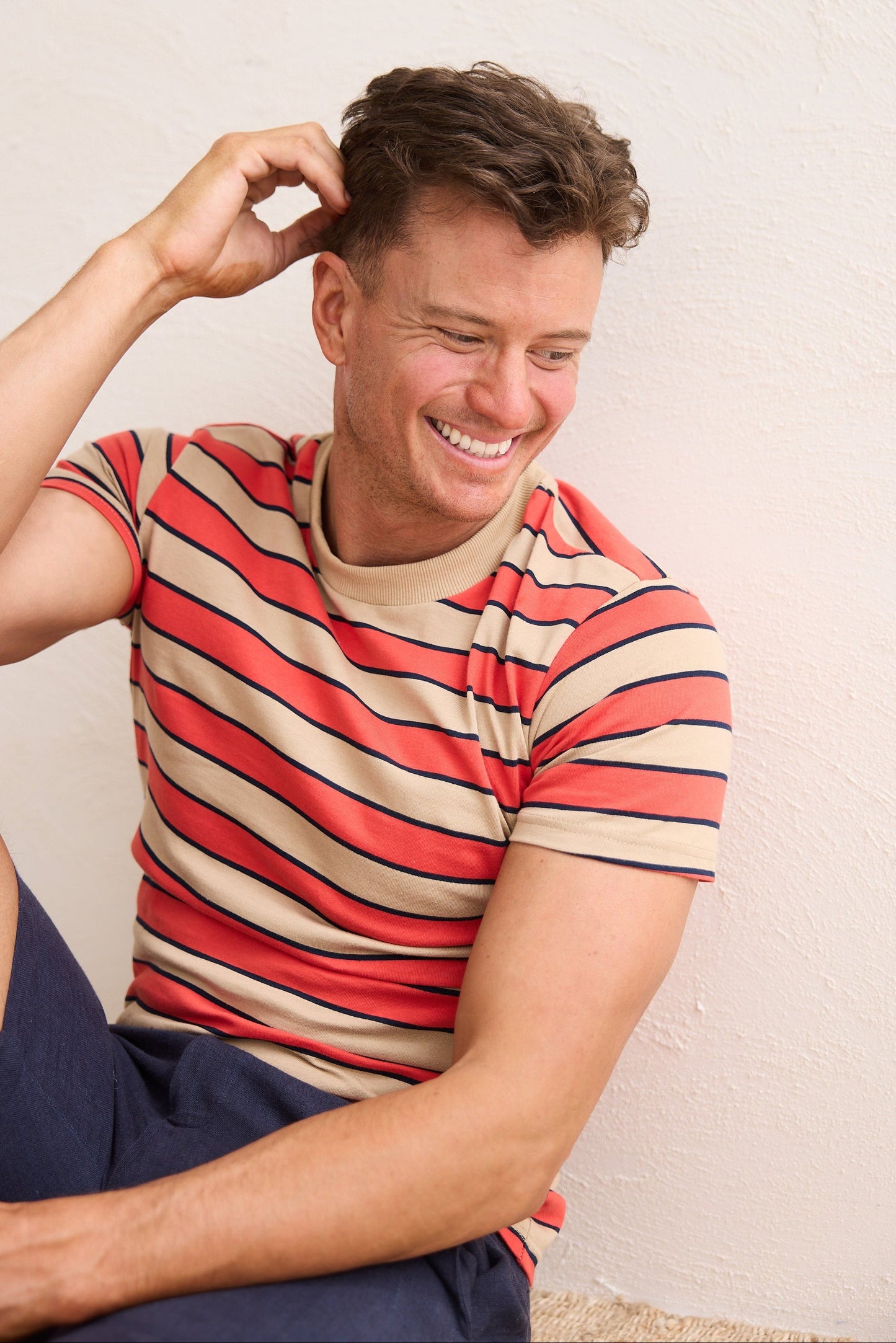 Man wearing a striped shirt sitting against a plain background