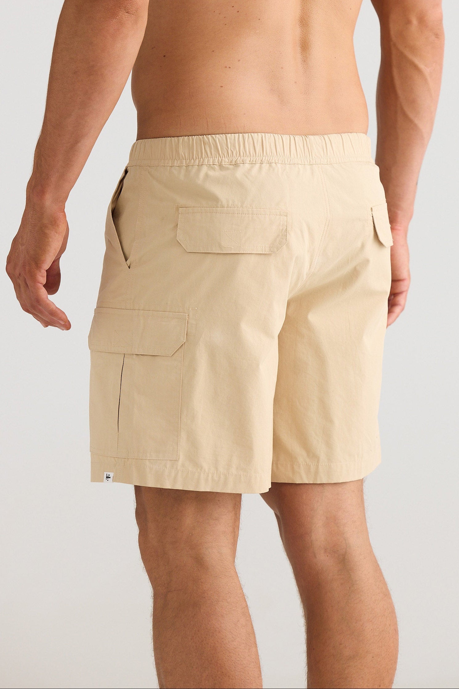 Man wearing beige cargo shorts on a plain background