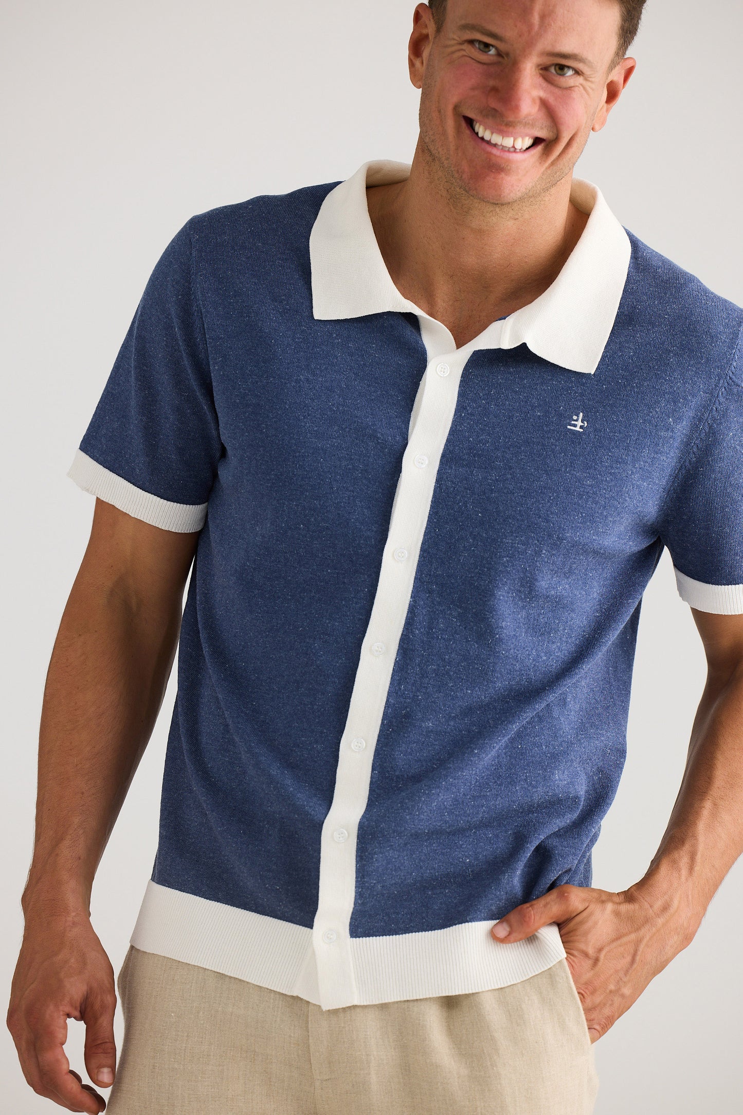 Man wearing a blue and white polo shirt with a visible brand logo on a plain background