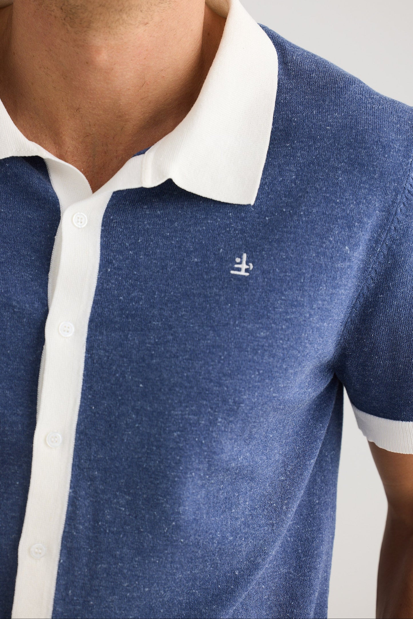 Close-up of a blue and white polo shirt with a small logo on a plain background