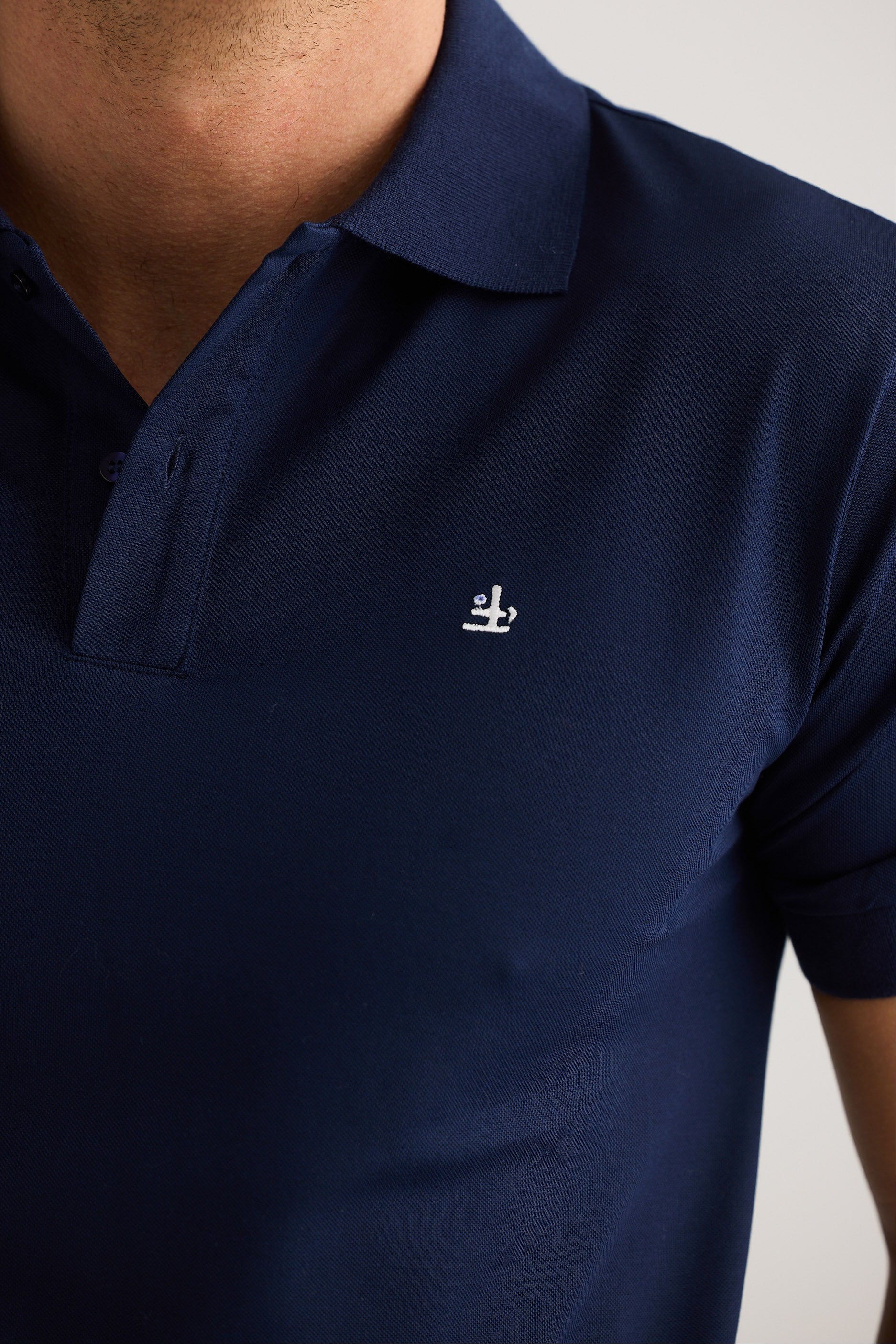 Navy blue polo shirt with a small white logo on a plain background