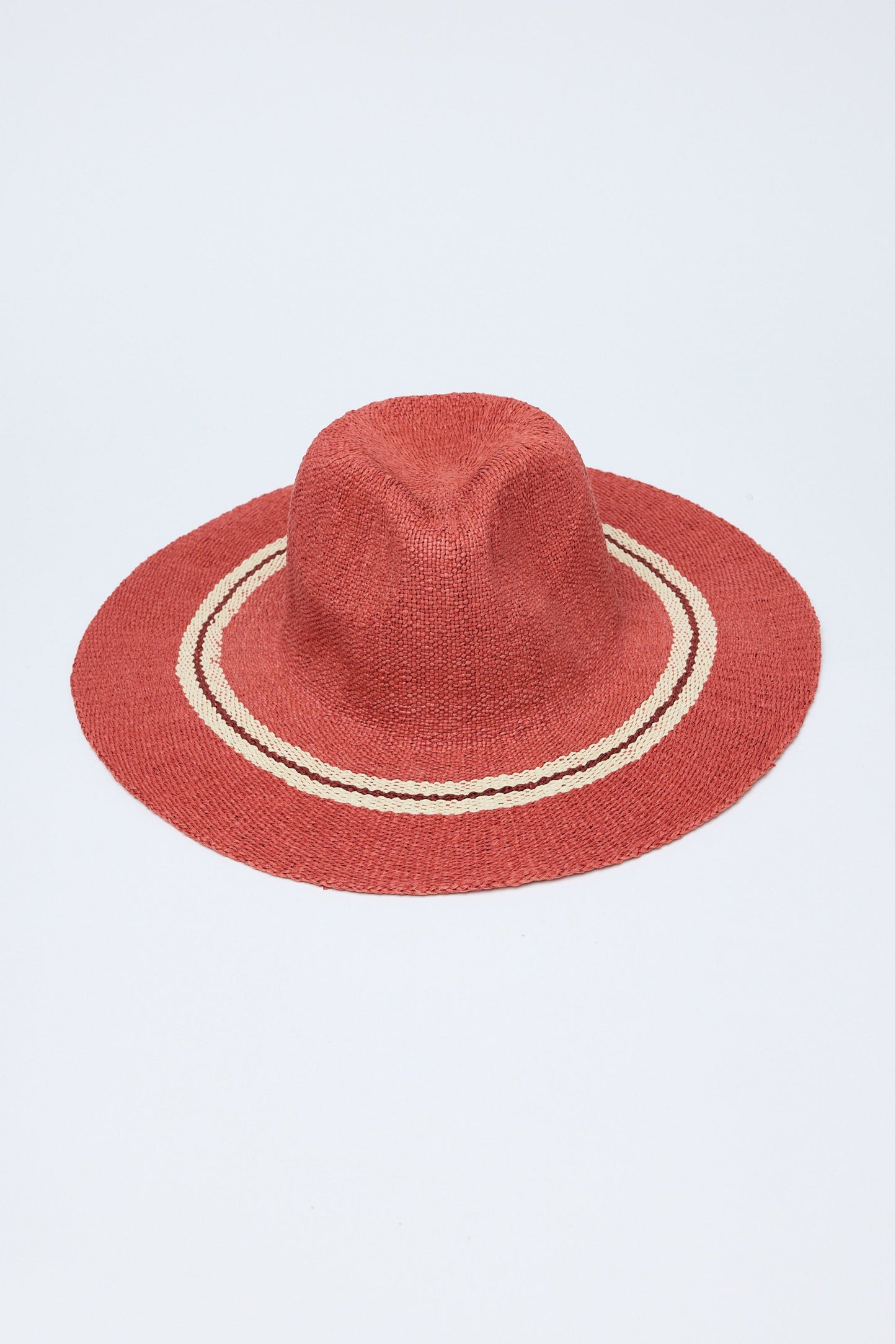 Red straw hat with a white band on a light gray background