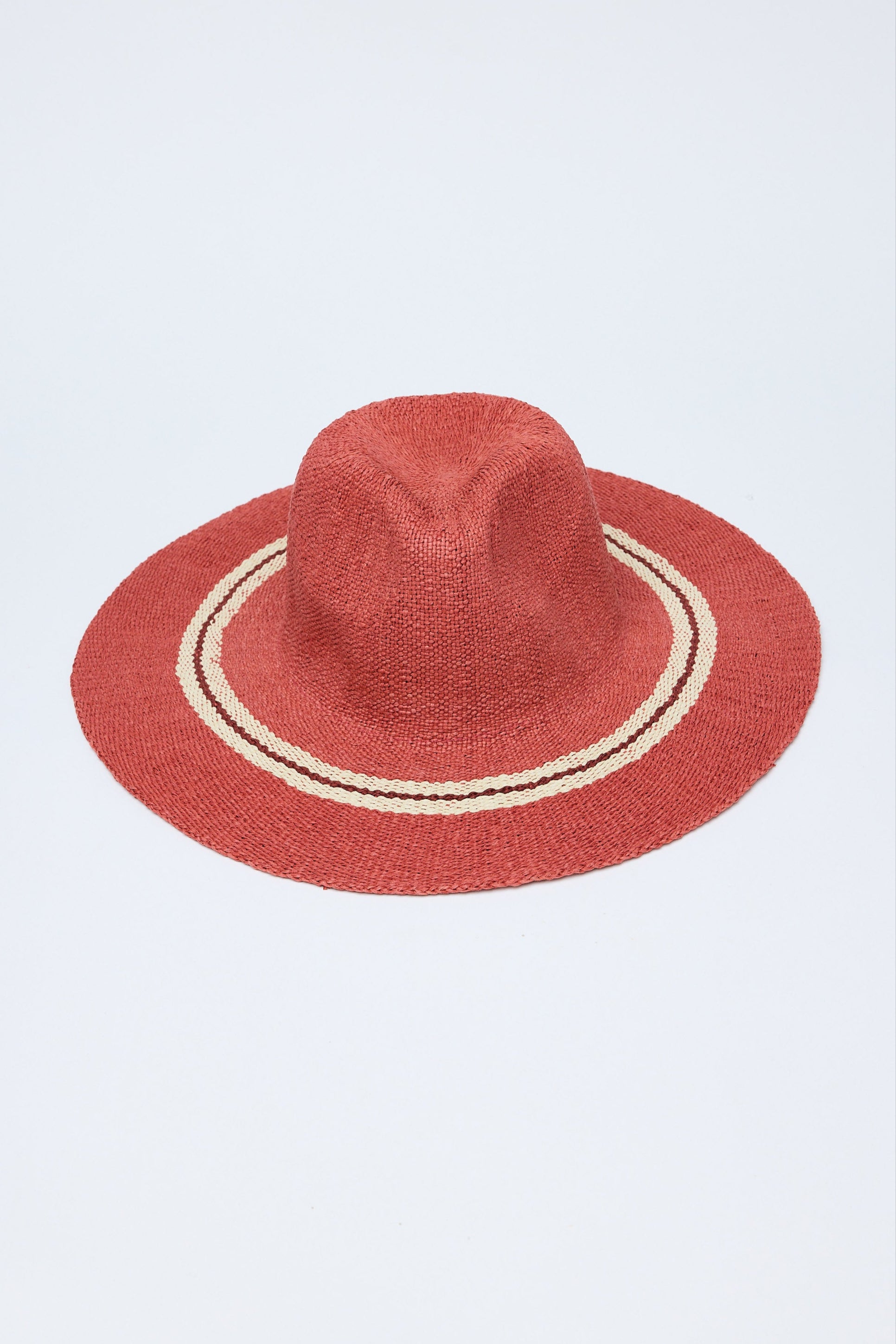 Red straw hat with a white band on a light gray background