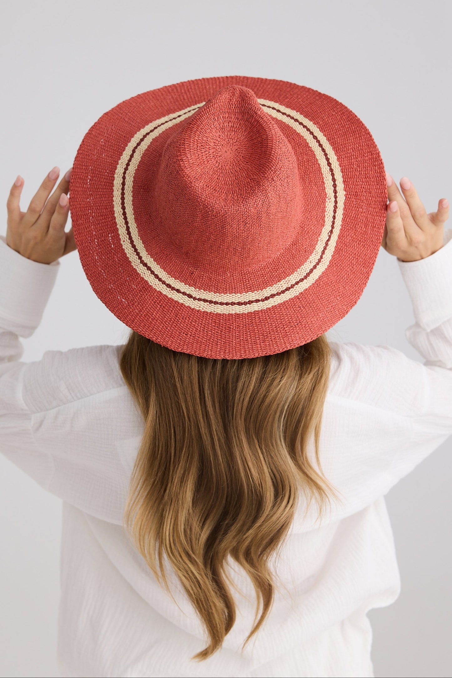 Person wearing a red straw hat with a white background