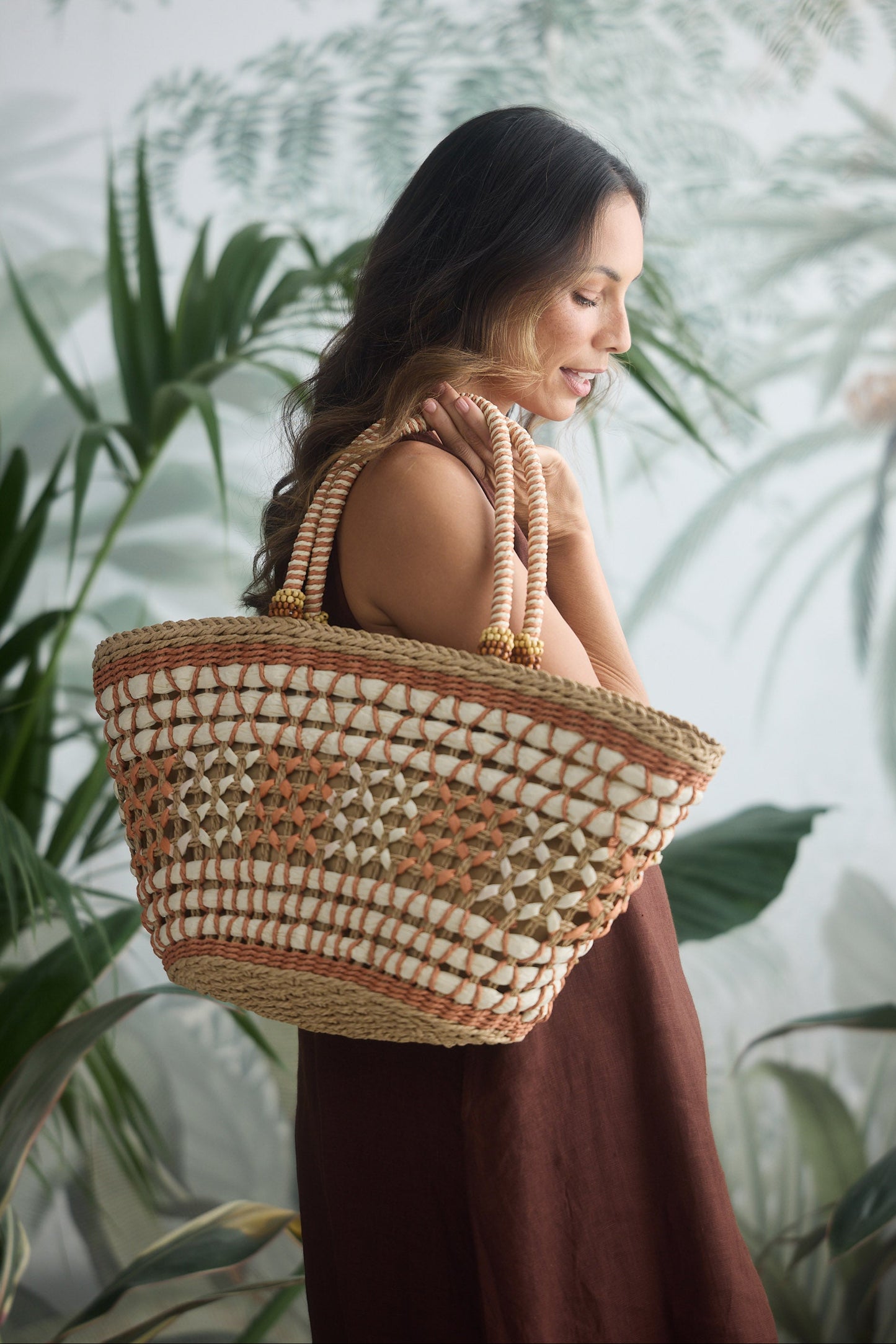 Woman holding a woven basket against a leafy green background