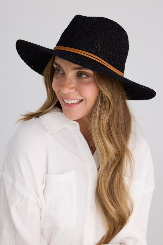 Woman wearing a black hat with a brown band on a white background