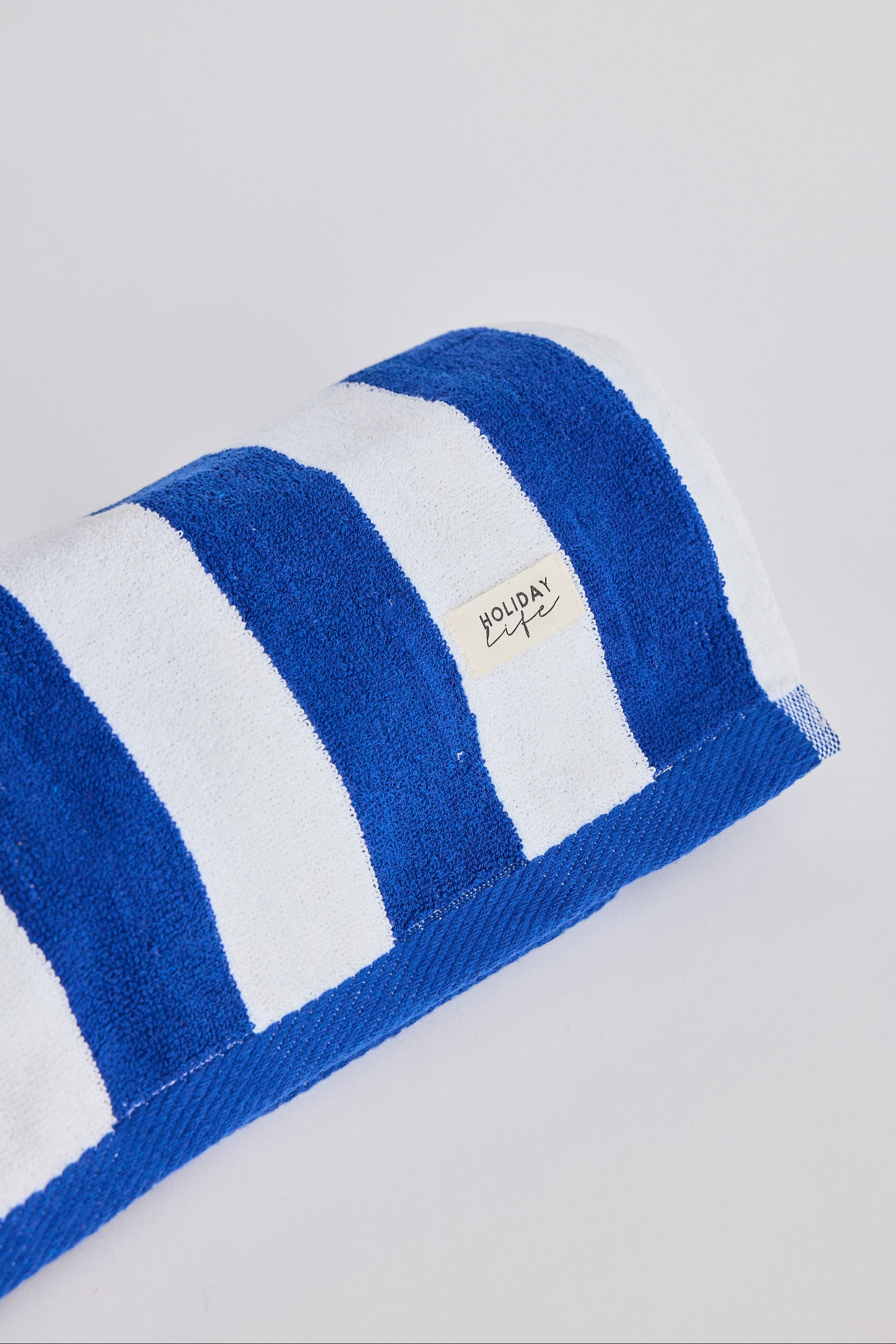 Blue and white striped towel with a brand logo on a light gray background