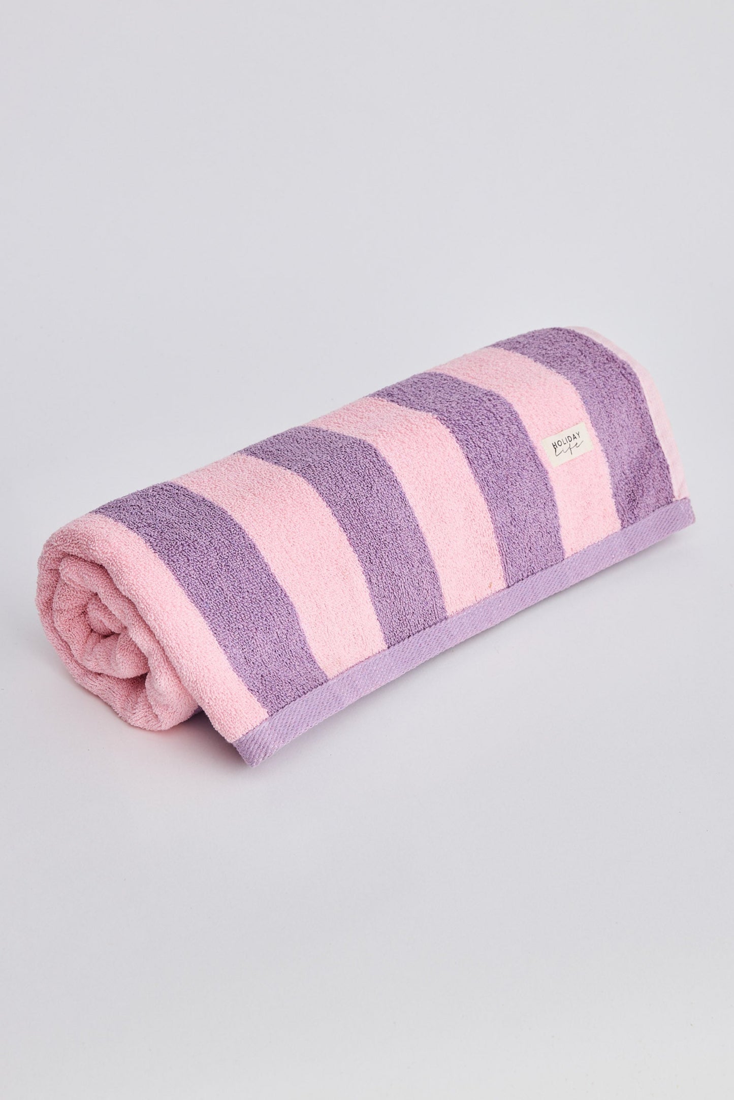 Folded towel with pink and purple stripes on a light gray background