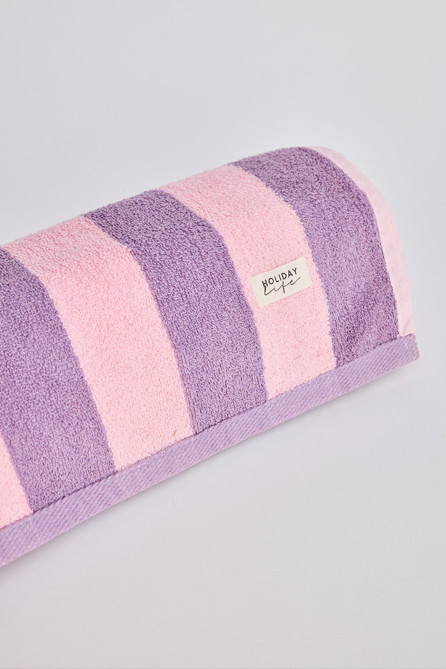 Striped towel with pink and purple horizontal stripes on a gray background