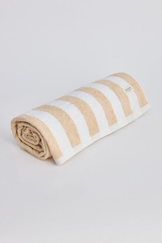 Rolled-up towel with beige and white stripes on a light gray background
