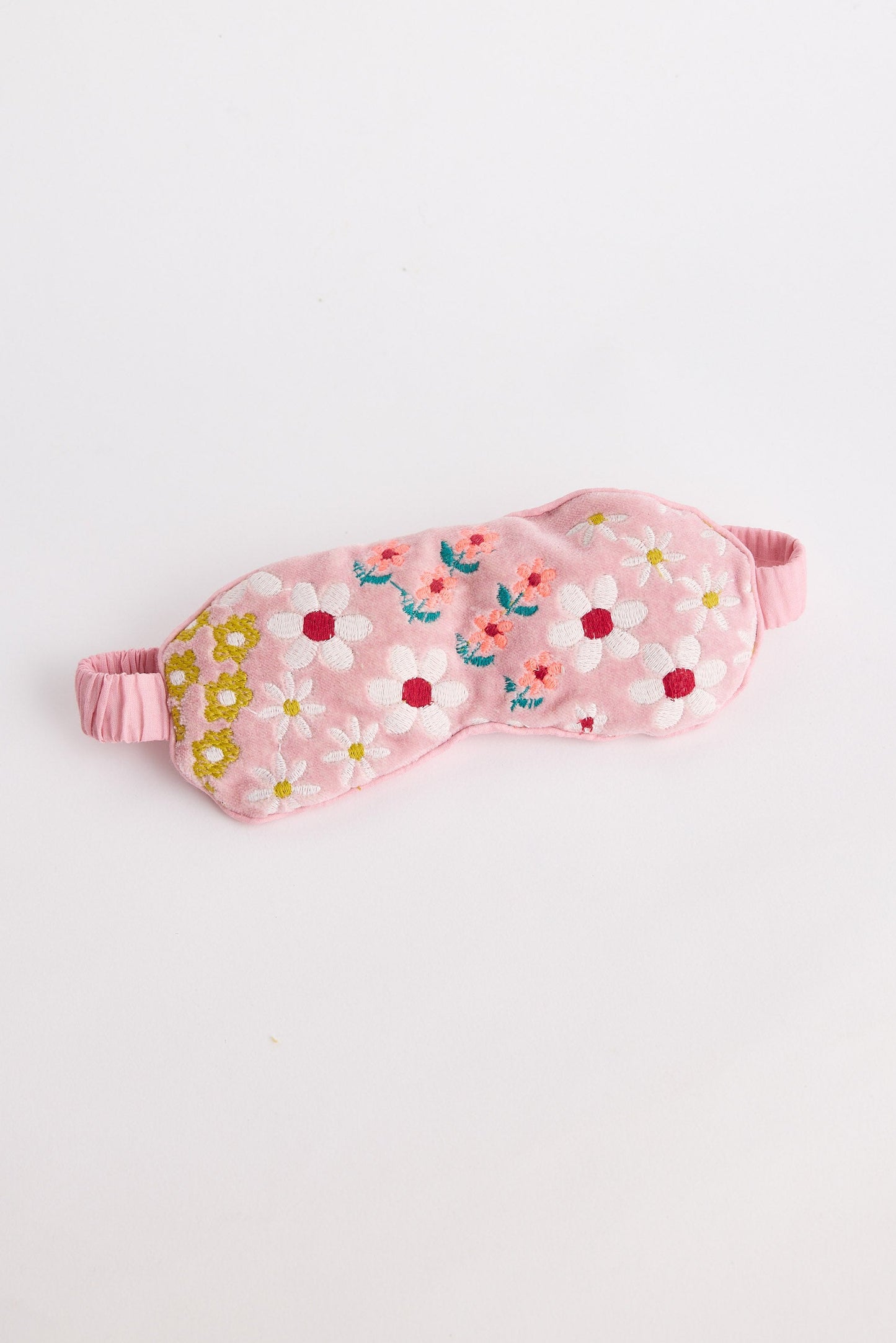 Pink sleep mask with floral pattern on a light gray background