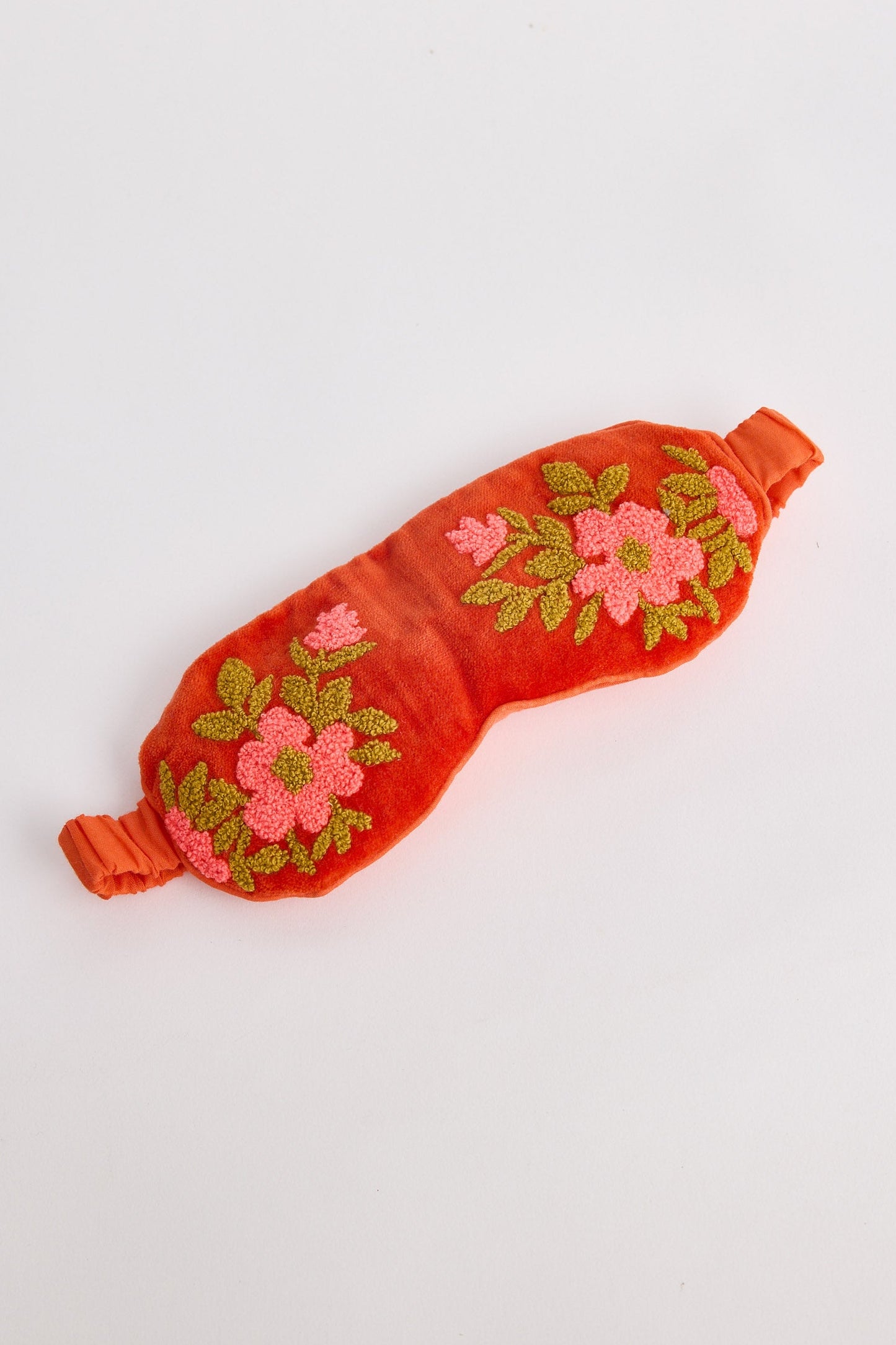 Red sleep mask with floral embroidery on a white background