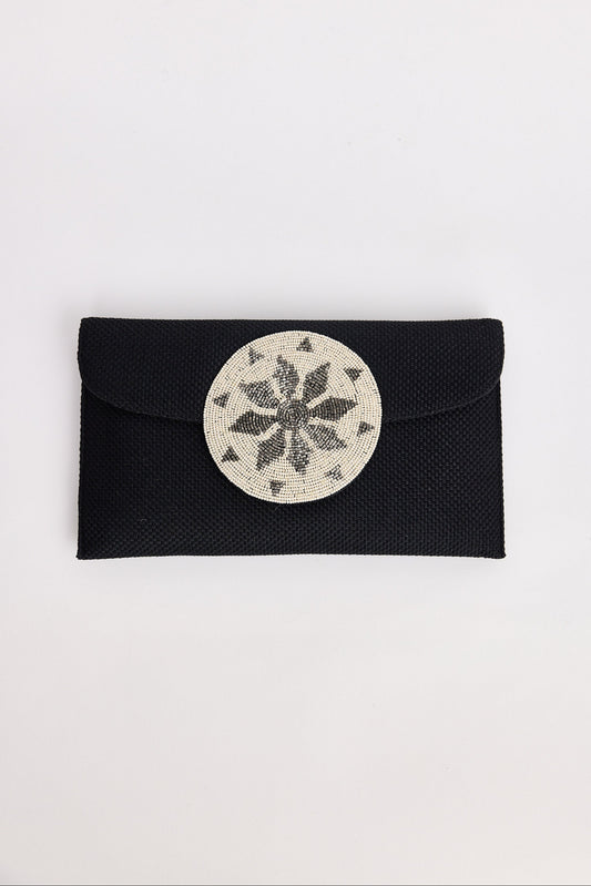 Black clutch with a circular silver design on a white background