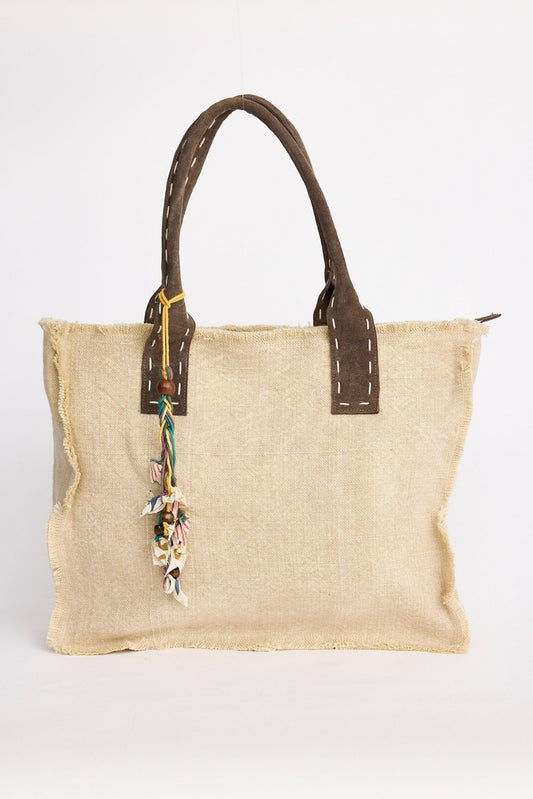 Jute bag with brown leather handles on a white background