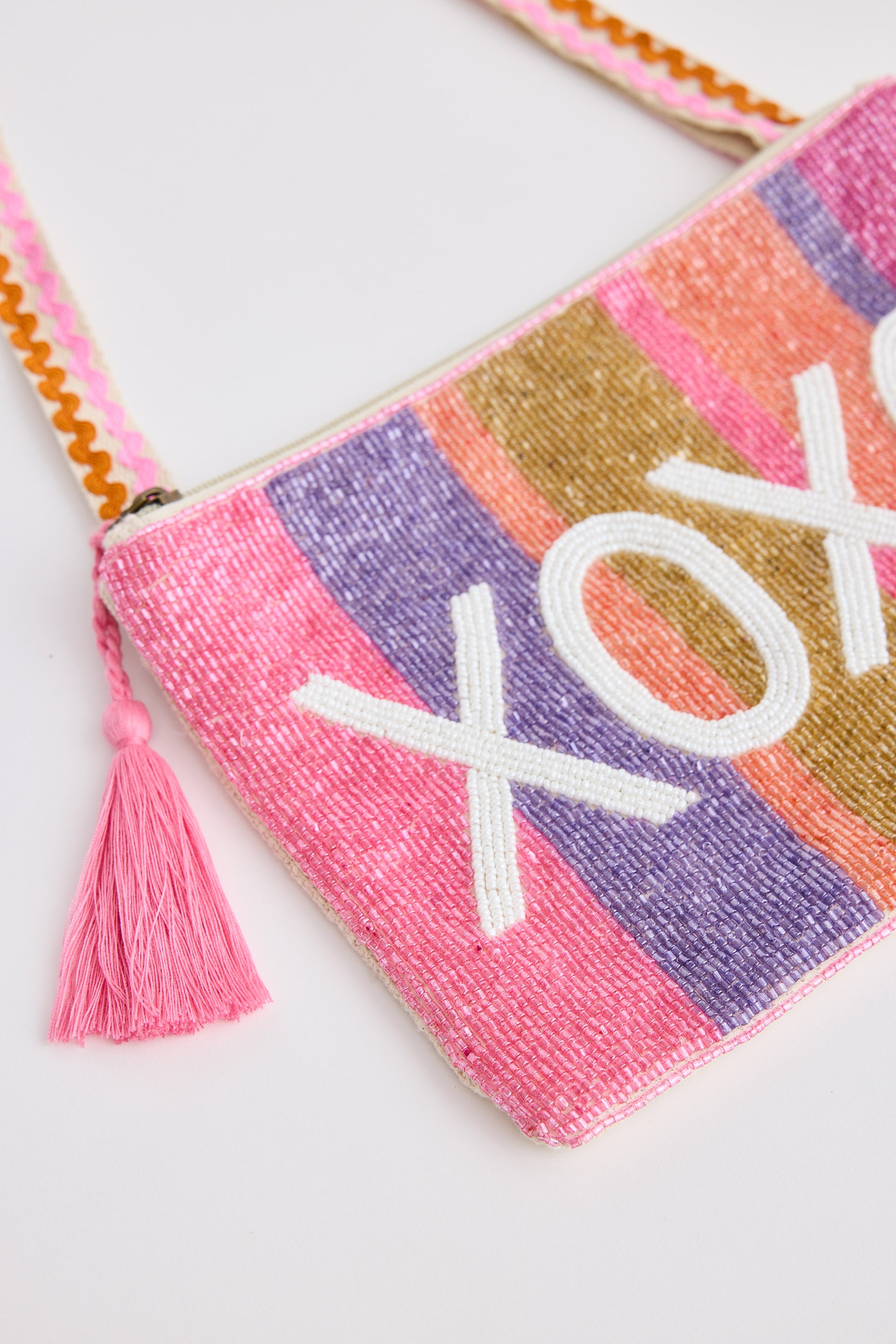 Colorful pouch with 'XOXO' embroidery and tassel on a white background