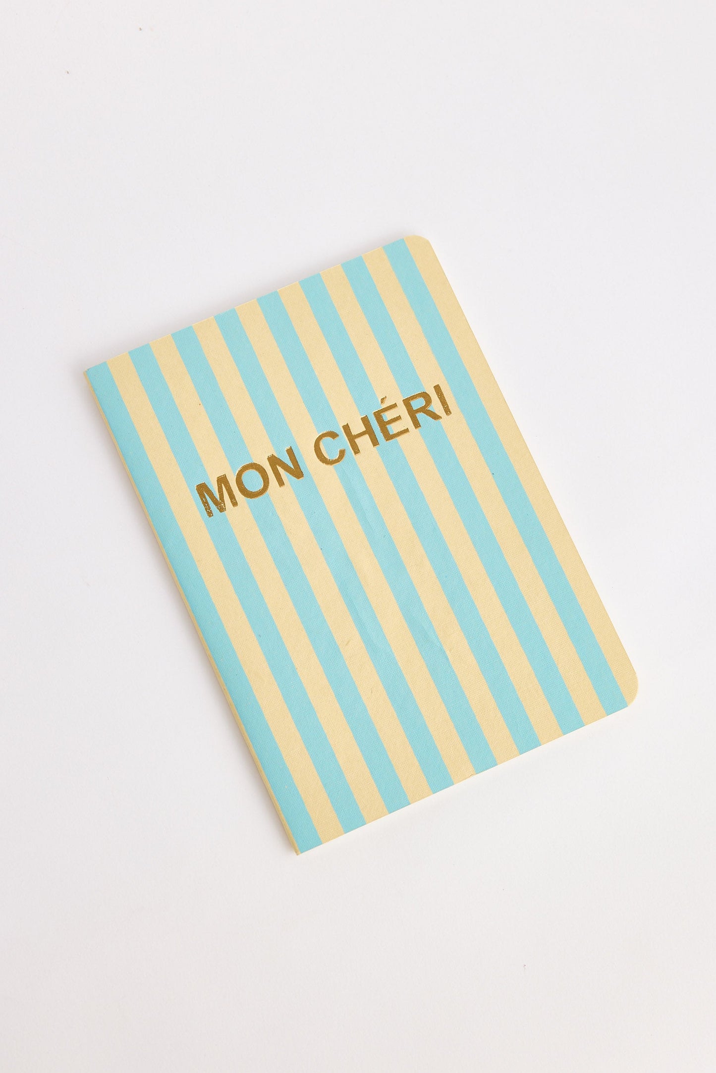 Notebook with blue and yellow striped cover and 'MON CHERI' text on a white background