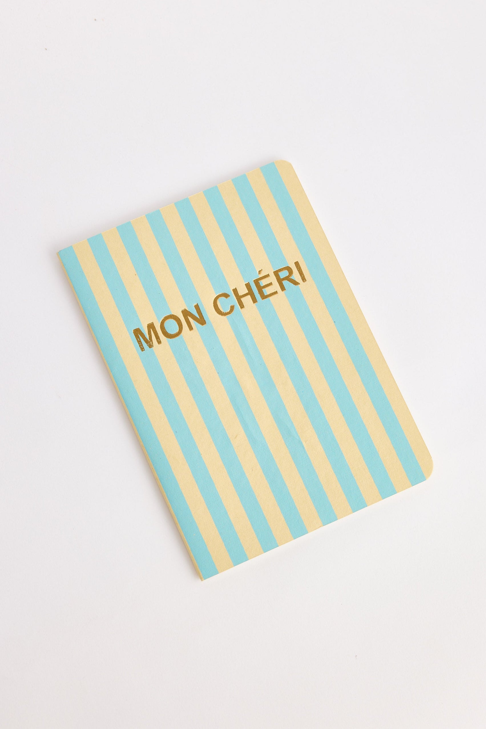 Notebook with blue and yellow striped cover and 'MON CHERI' text on a white background