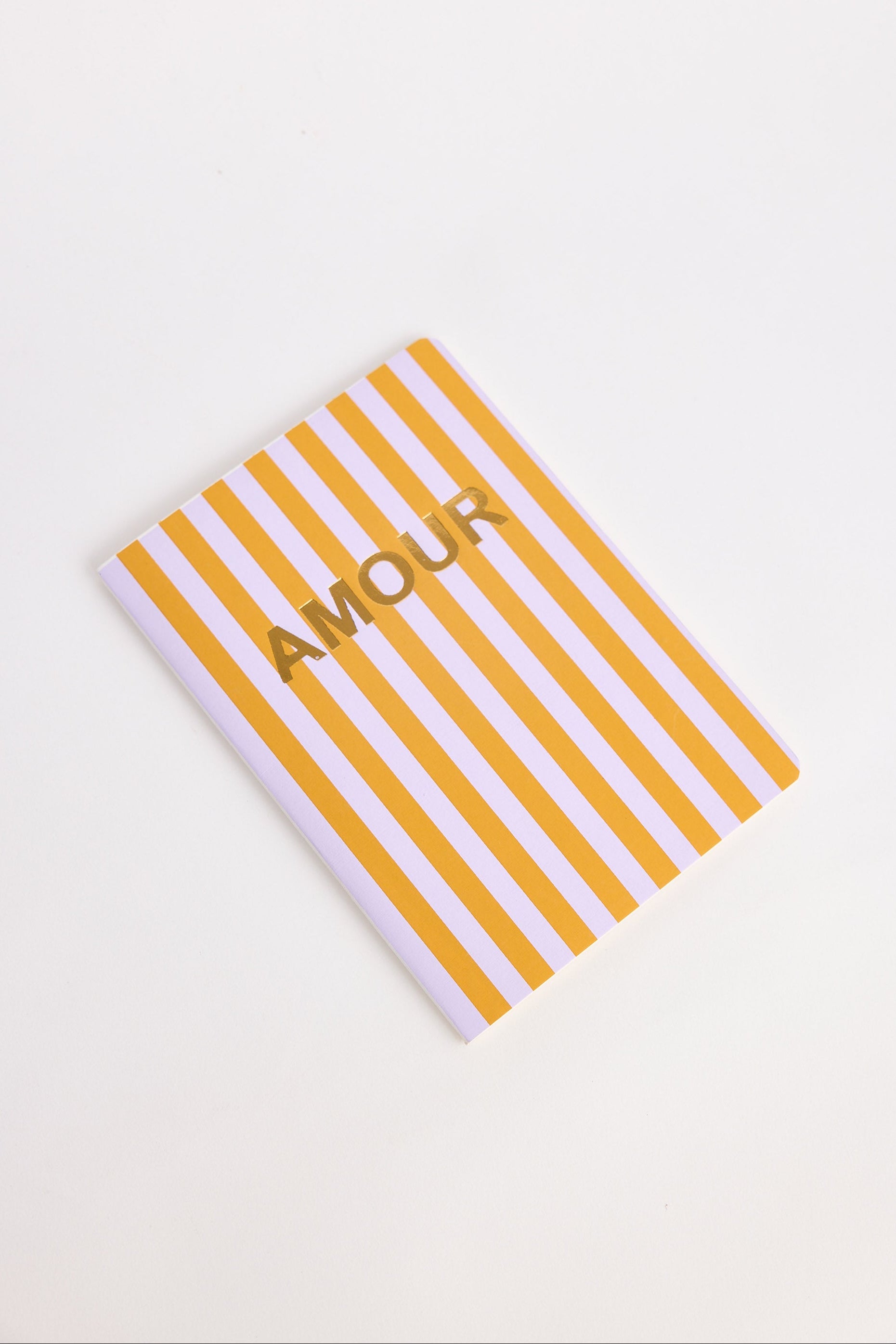 Notebook with orange and lilac striped cover and 'Amour' text on a white background