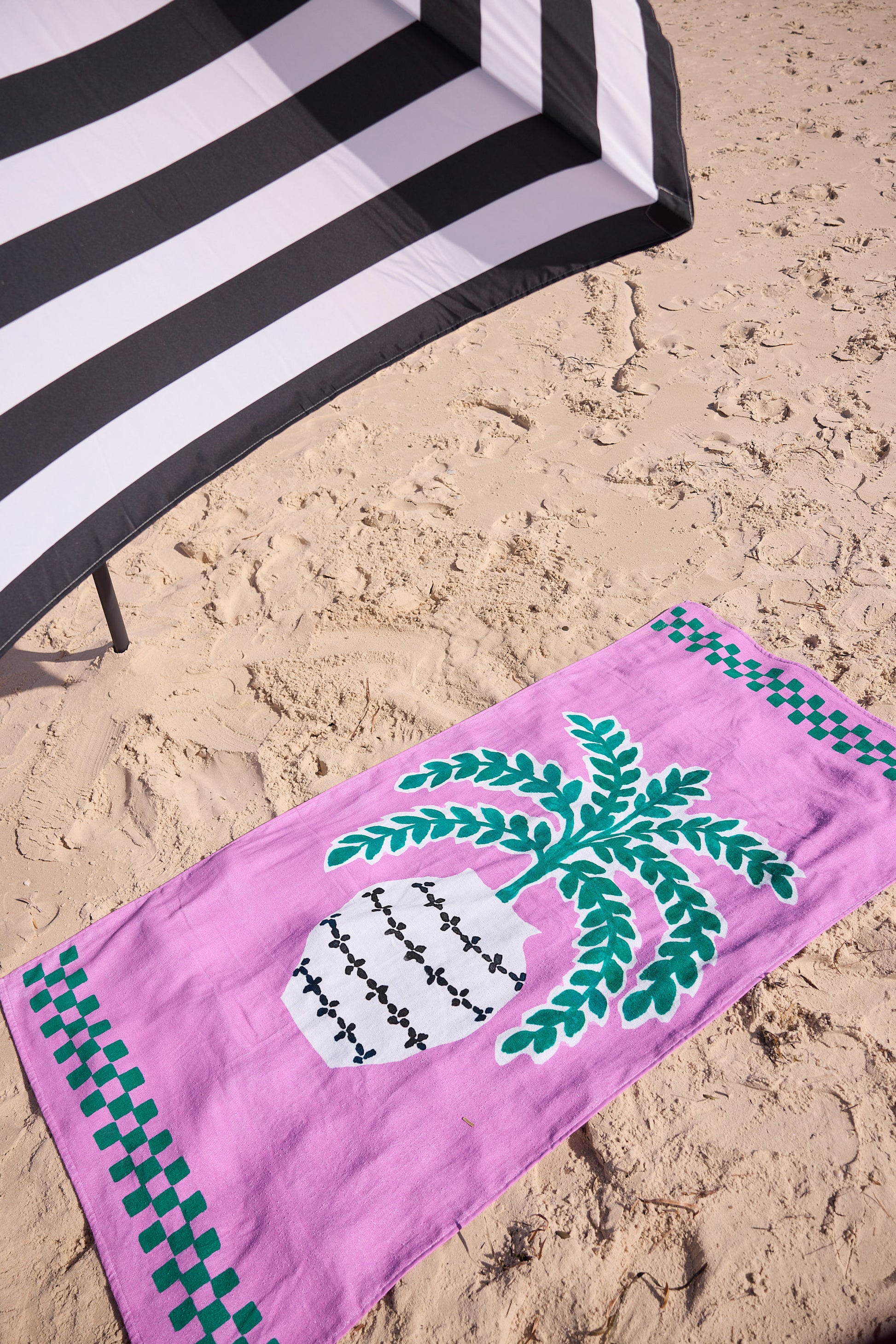 Pink beach towel with green design on sand