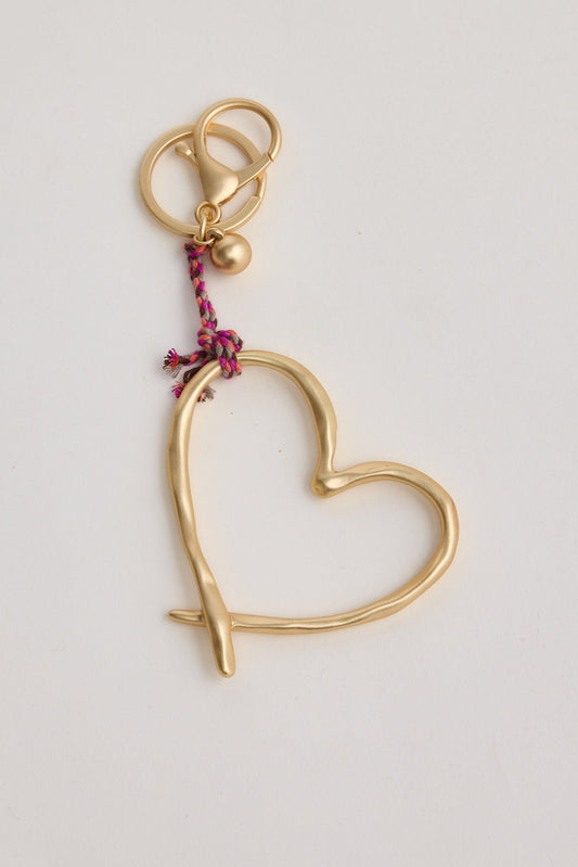Gold heart-shaped keychain with a pink string on a light gray background