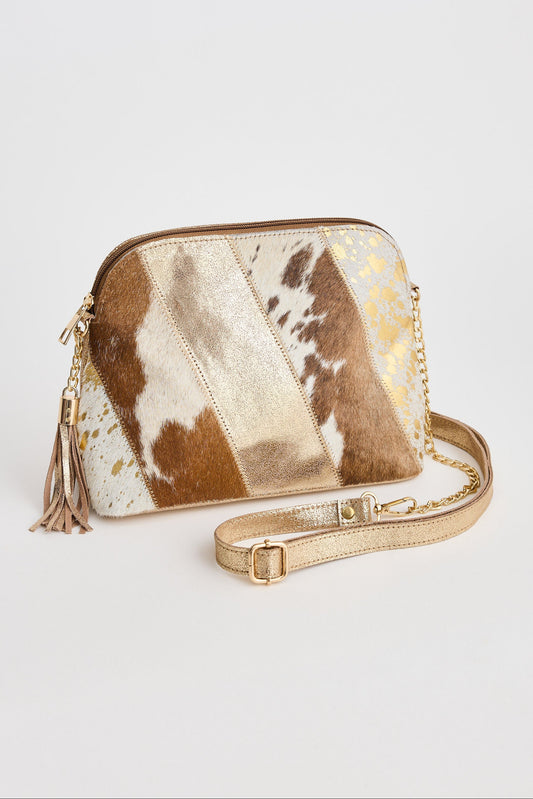 Gold and brown cowhide leather crossbody bag with tassel on a light gray background