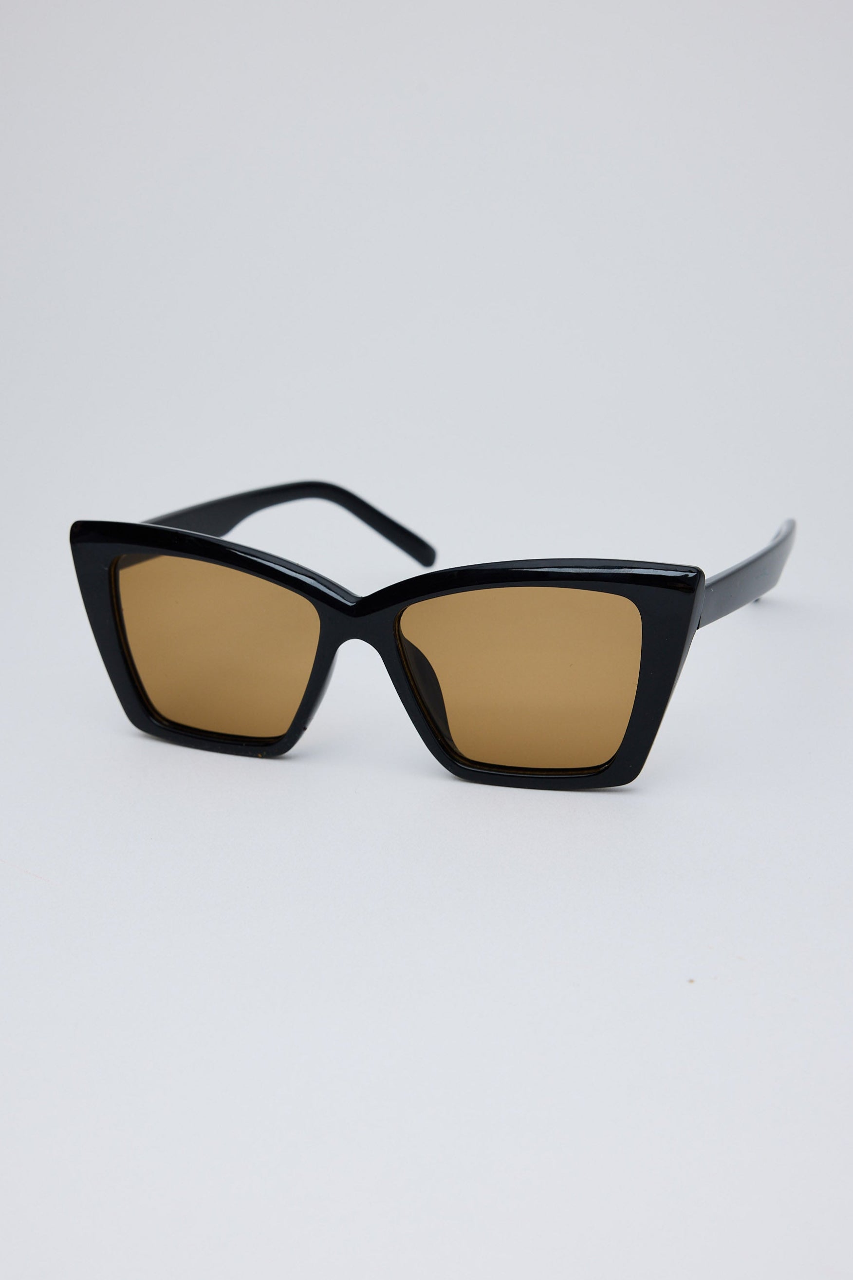 Black sunglasses with brown lenses on a white background