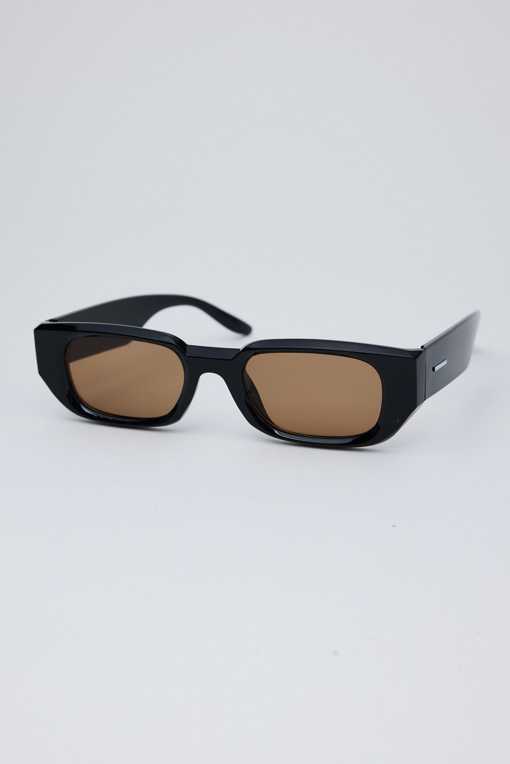 Black sunglasses with brown lenses on a light gray background