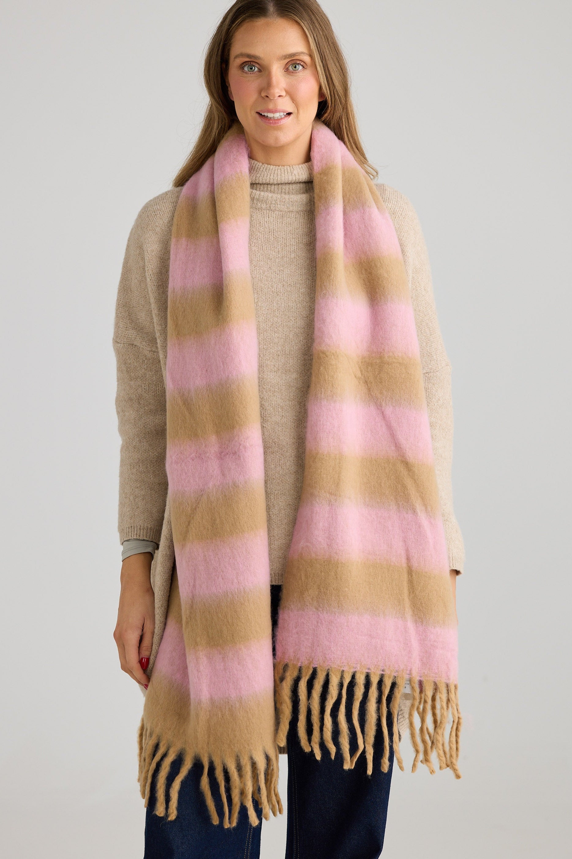 Woman wearing a pink and beige striped scarf on a plain background