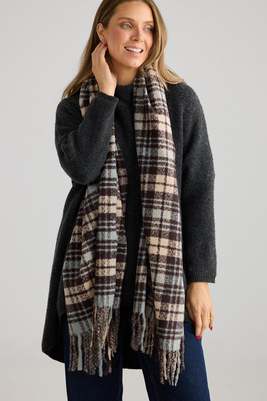 Woman wearing a plaid scarf and dark jumper on a plain background