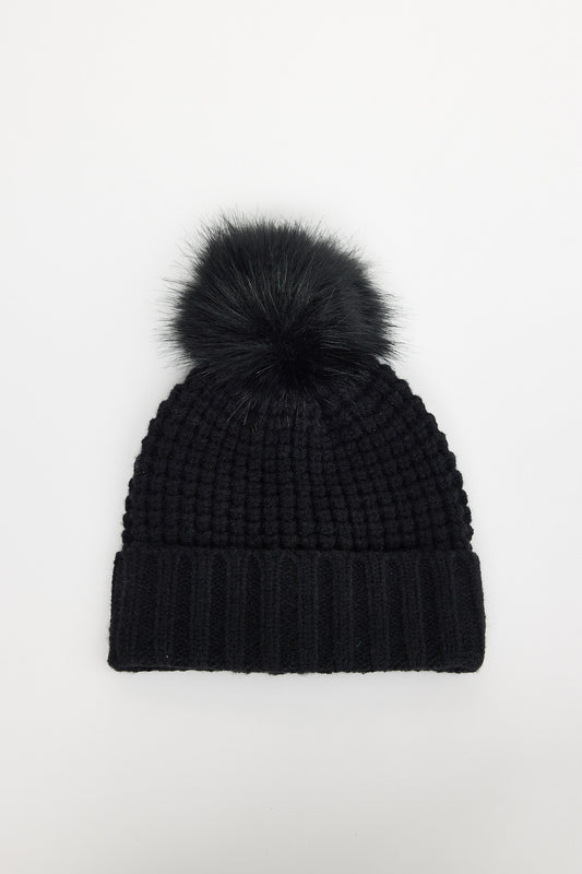 Black knit beanie with a pom-pom on a white background