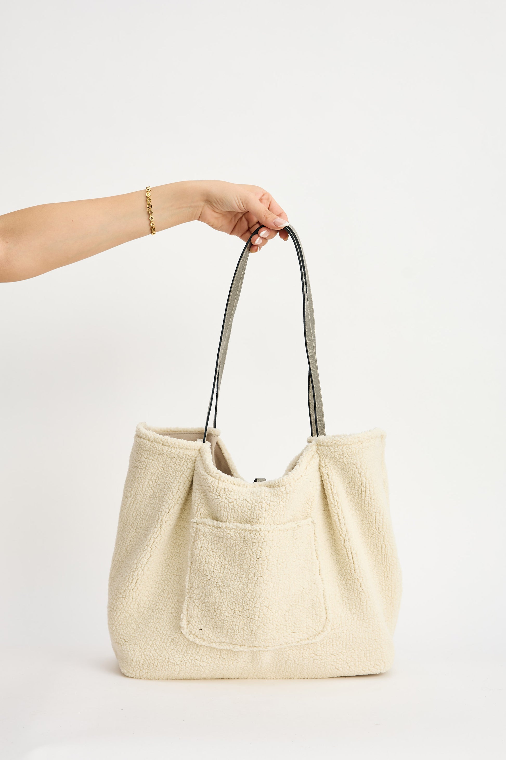 Beige tote bag held by a hand on a white background