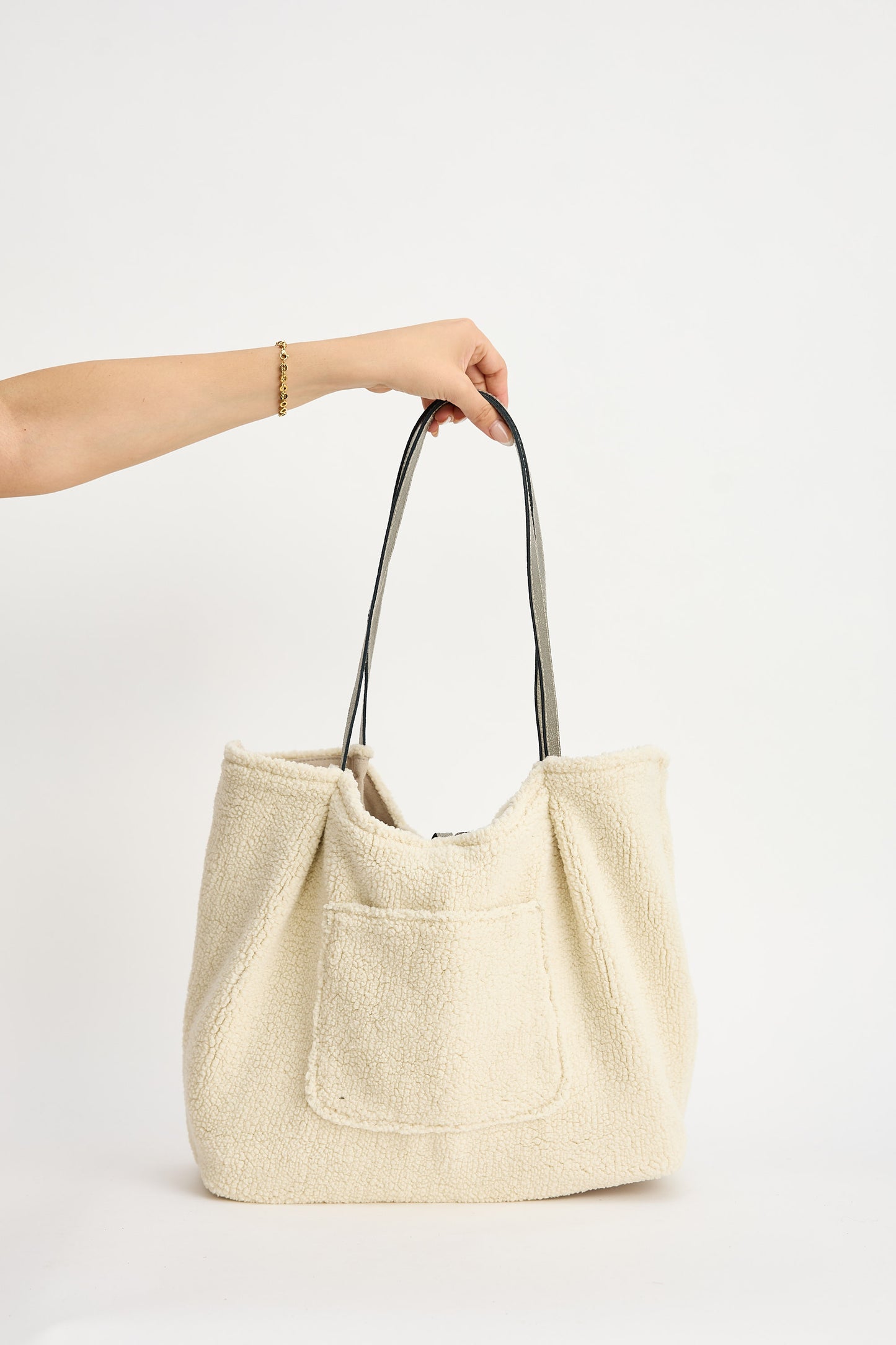 Beige tote bag held by a person on a white background