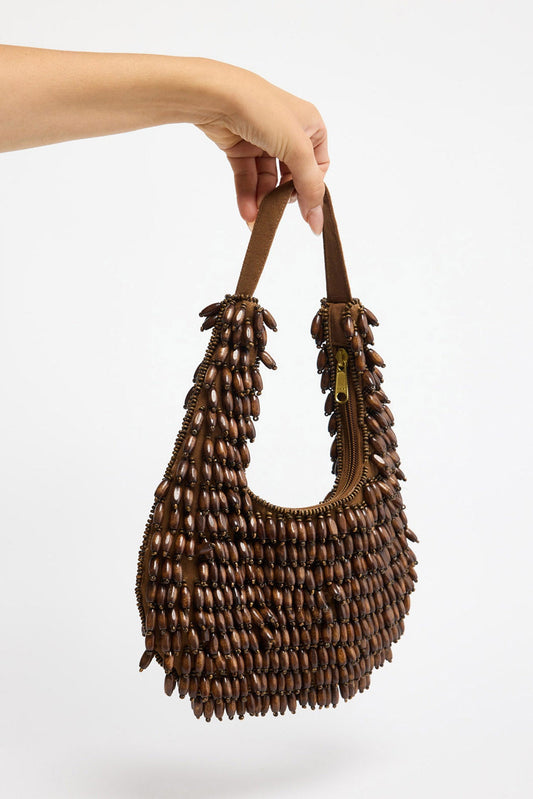 Half-moon shaped beaded clutch bag in chocolate brown and cream tones with a diamond lattice pattern, floral bead accents and gold-tone chain strap, shown hanging against a white background