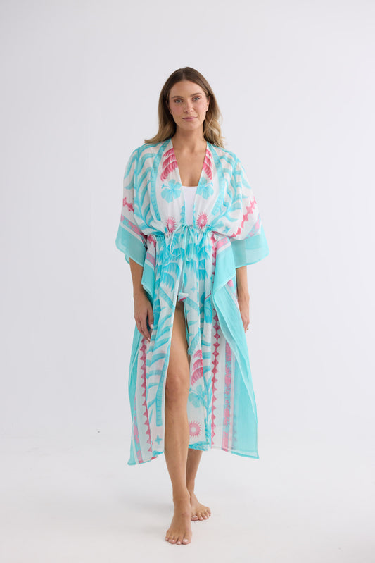 Model wearing Asta Long Kaftan in azure palm, front view. Open front with a drawstring waist tie.