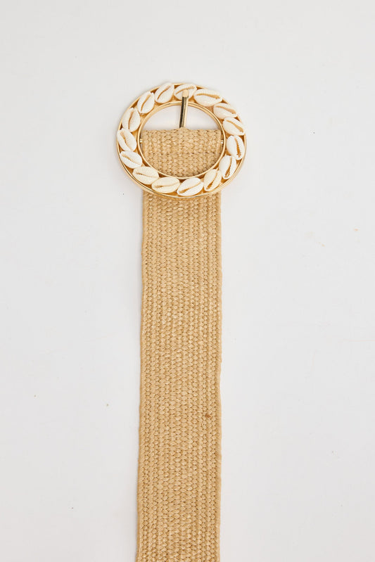 Shelly Belt in natural - beige stretch belt with a gold circular buckle framed in white cowrie shells, flat lay