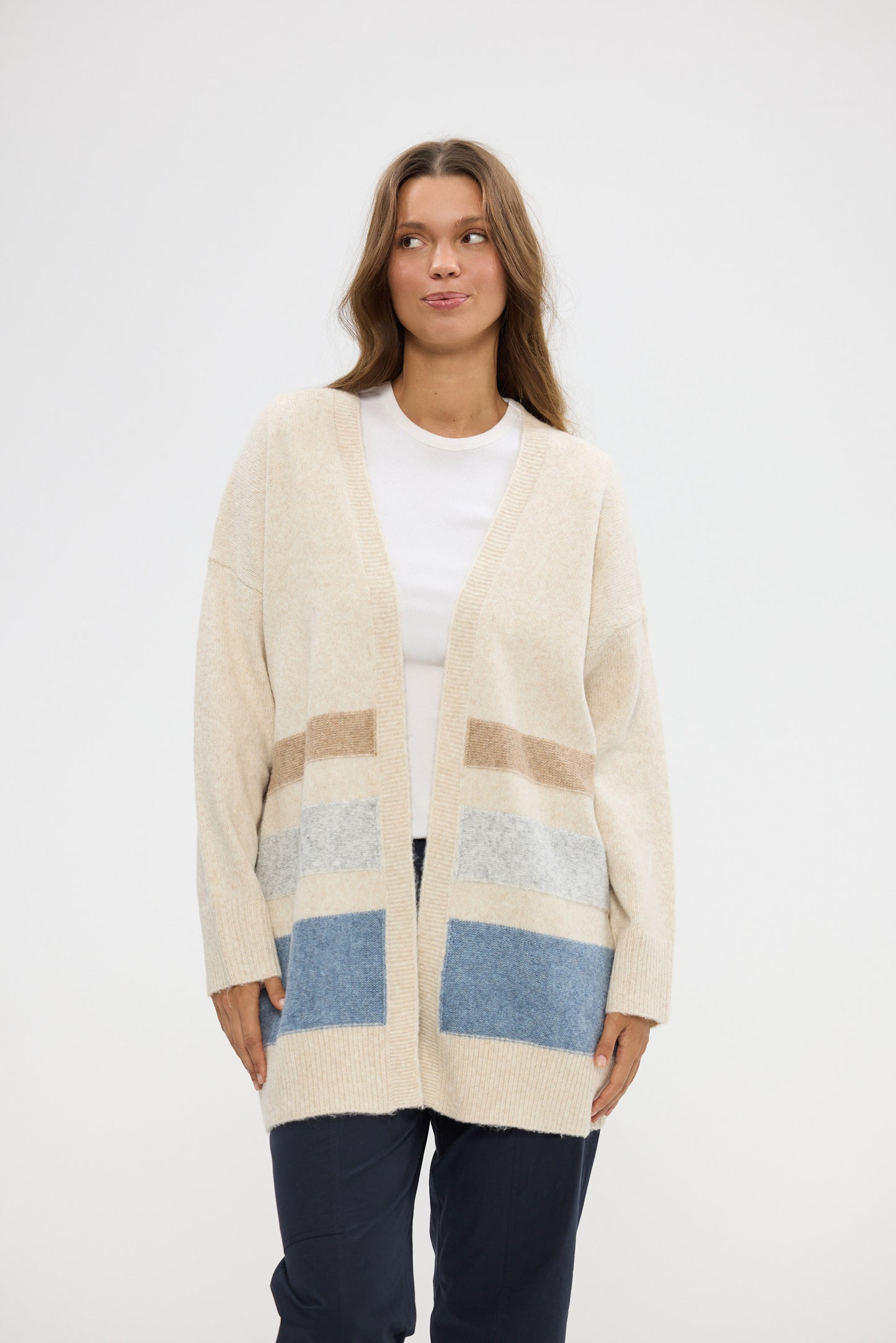 Woman wearing a beige cardigan with color-blocked pockets on a white background