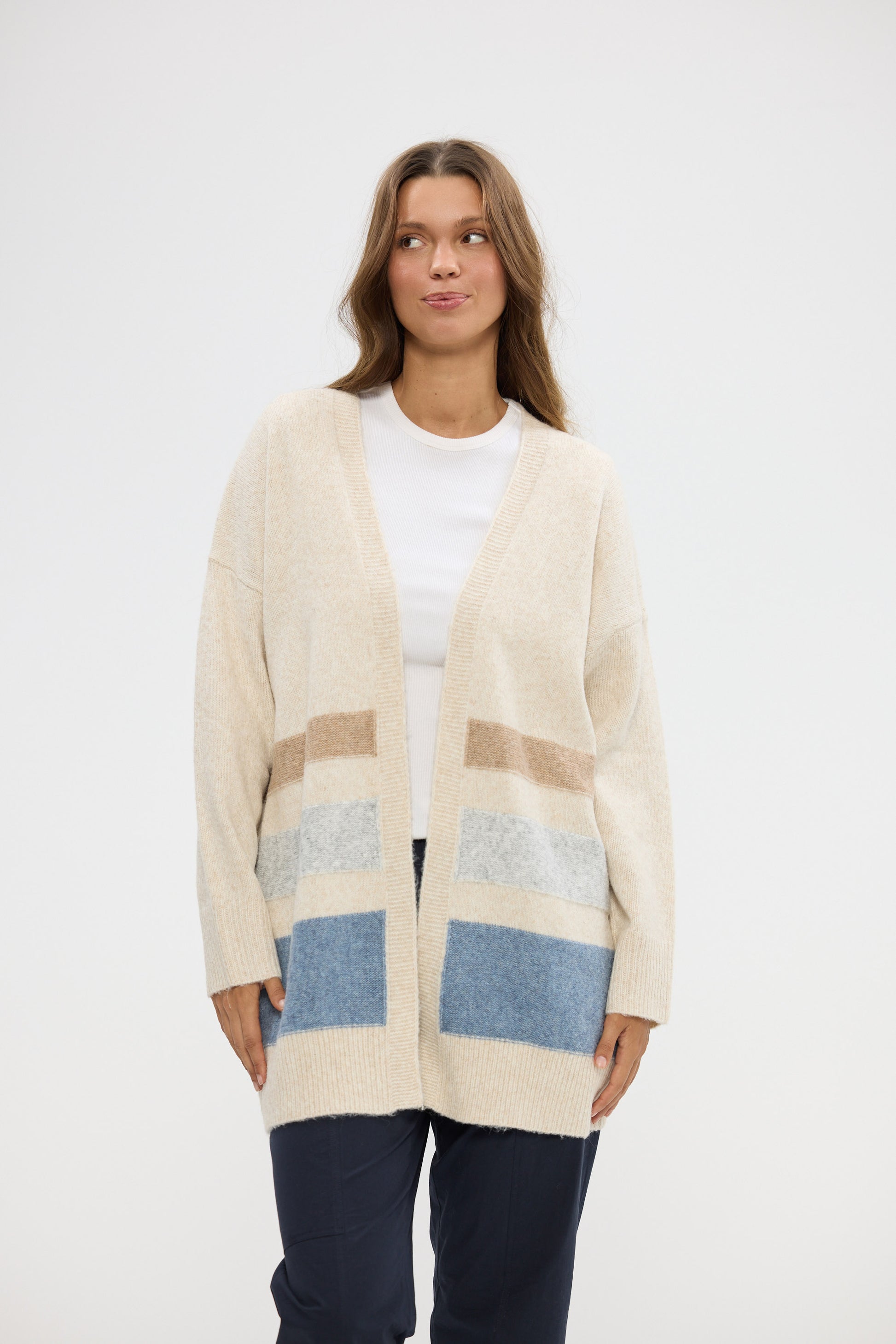 Woman wearing a beige cardigan with color-blocked pockets on a white background