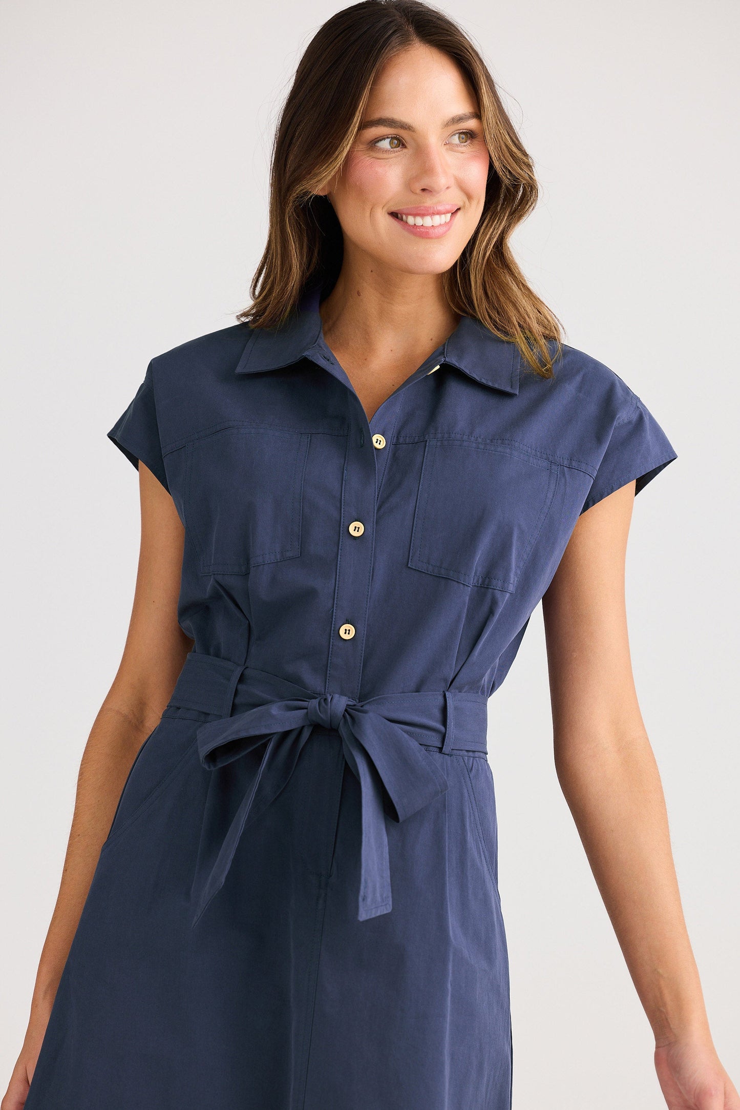 Woman wearing a navy blue dress with a belt on a white background