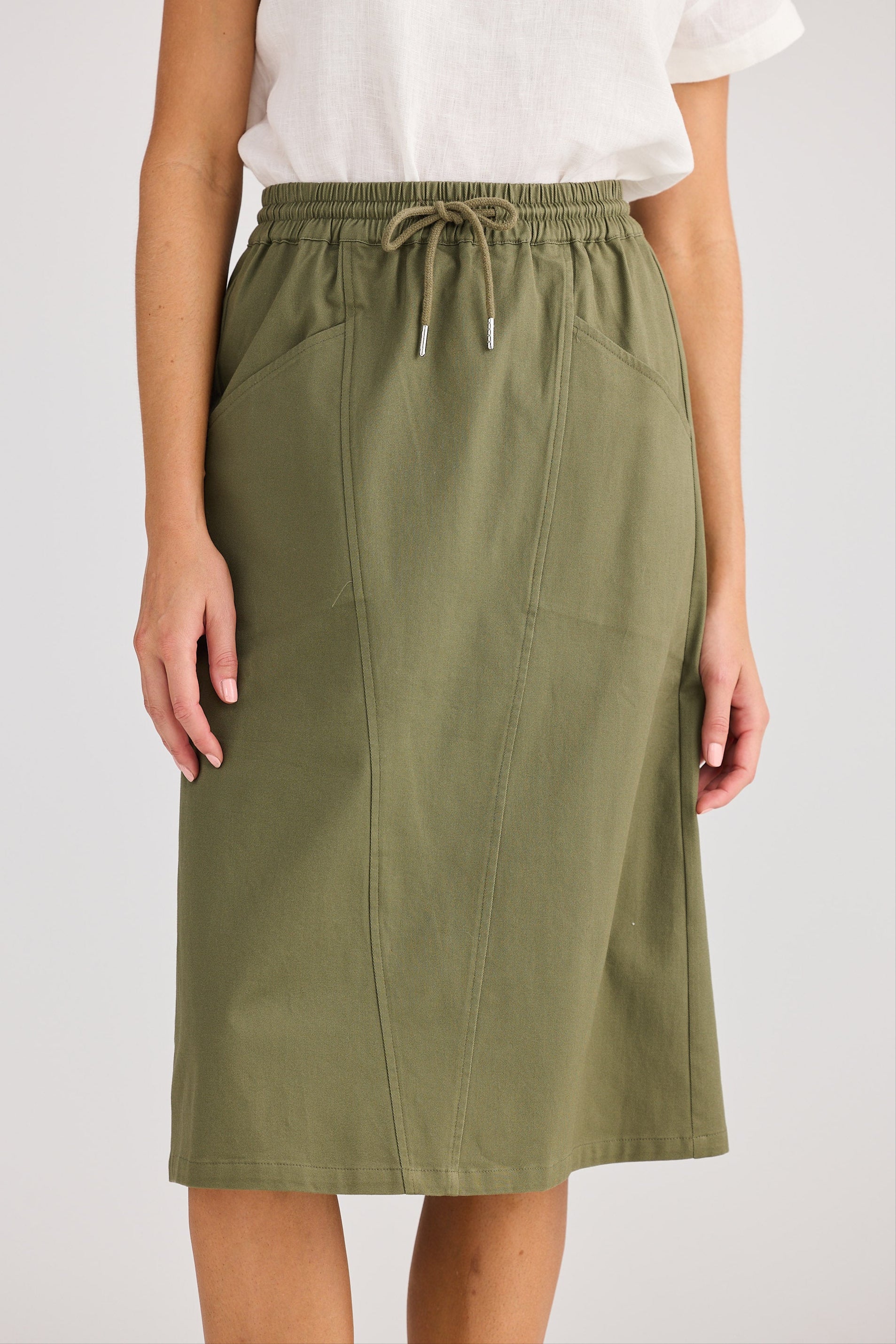 Person wearing a green skirt with a white top on a plain background